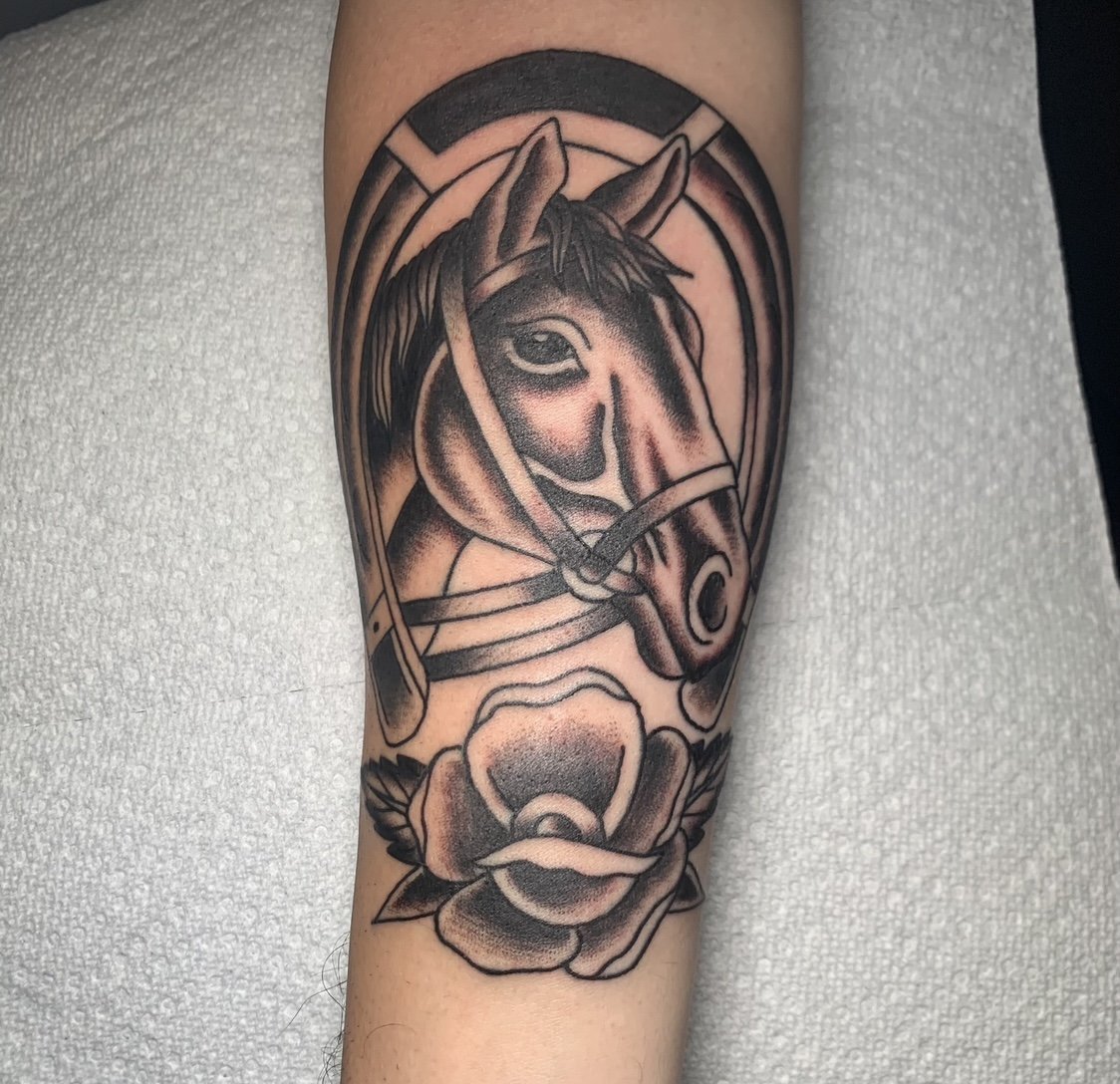 Tattoo of a horse's head with a flower below, rendered in black ink with shading.
