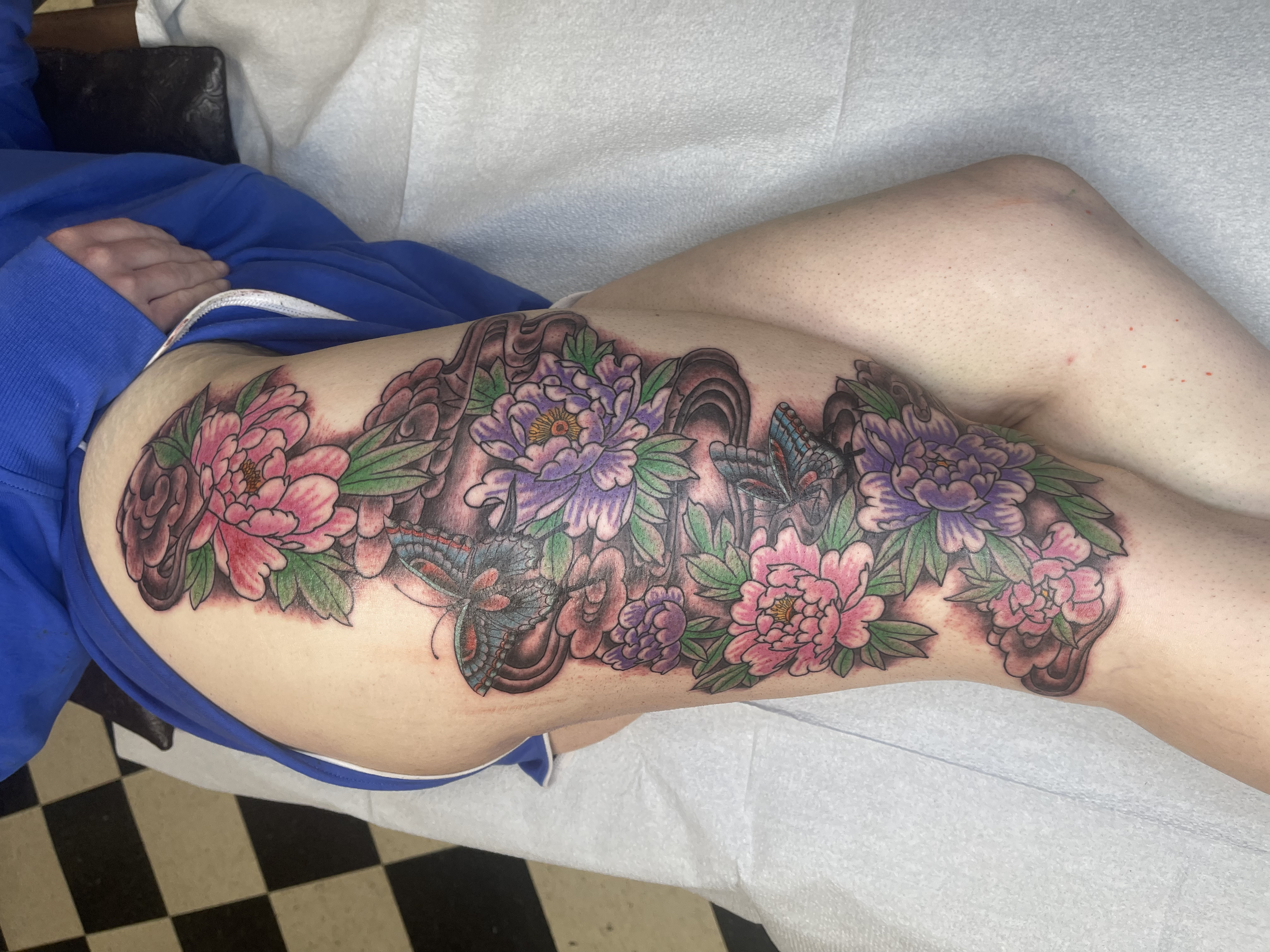A colorful tattoo of flowers and butterflies on a person's side.