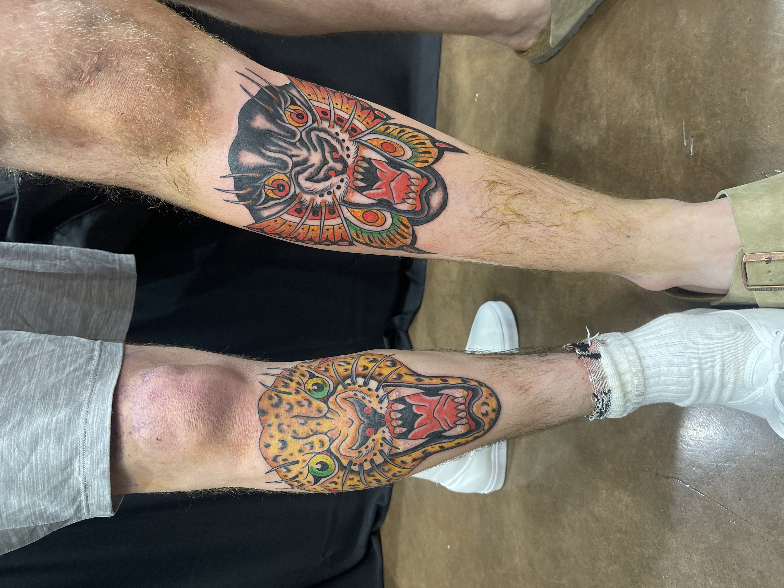 Colorful tiger face tattoo on a person's lower leg, featuring vibrant orange, black, and green details.