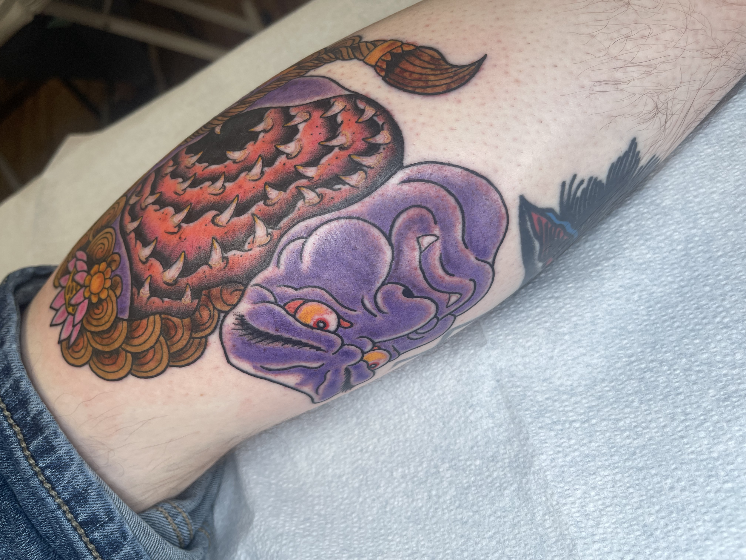 Colorful tattoo of a snake coiled around a purple brain on a person's arm.