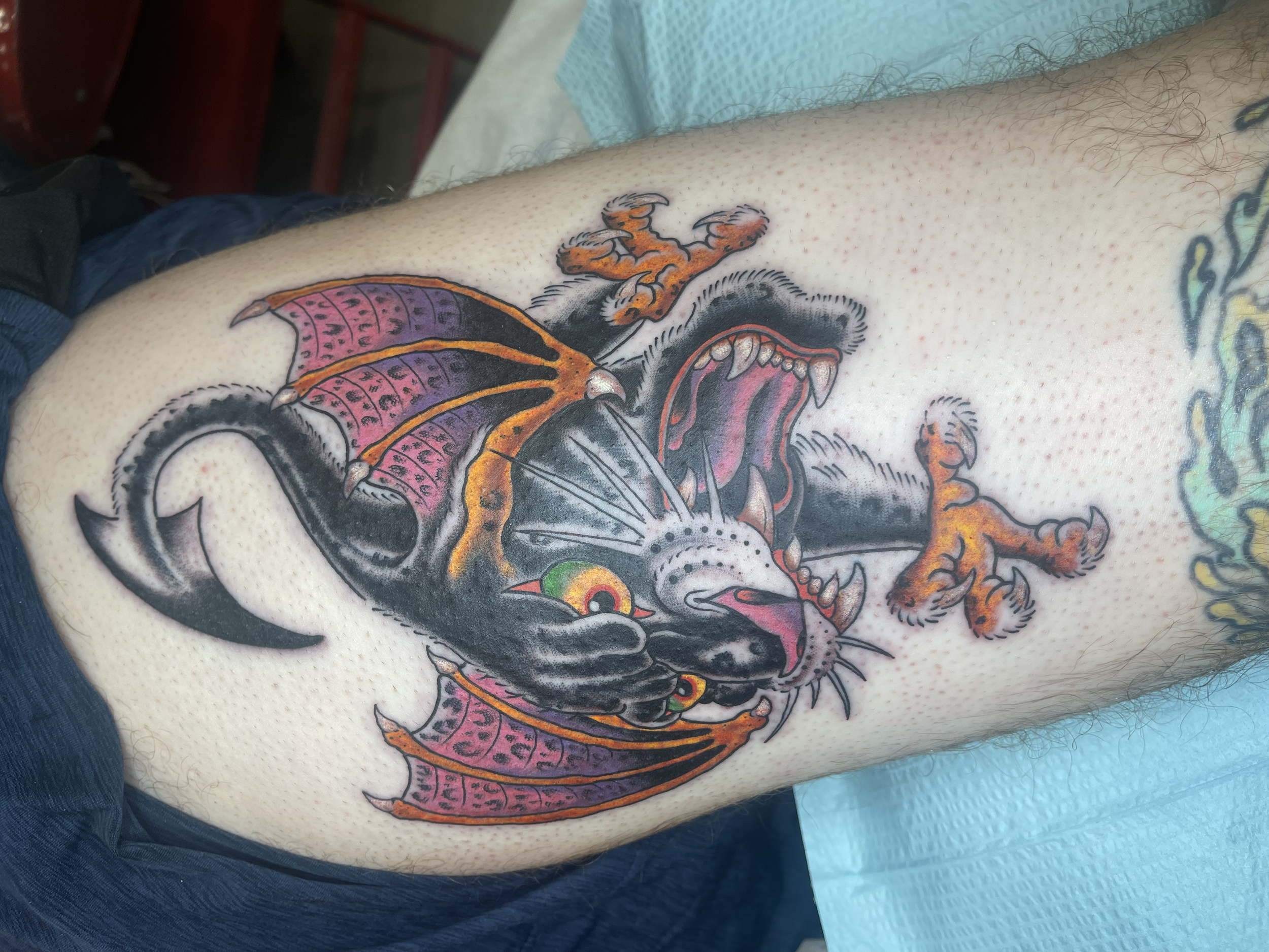 A colorful tattoo of a fierce dragon on a person's chest, with vivid orange, pink, purple, and black details.