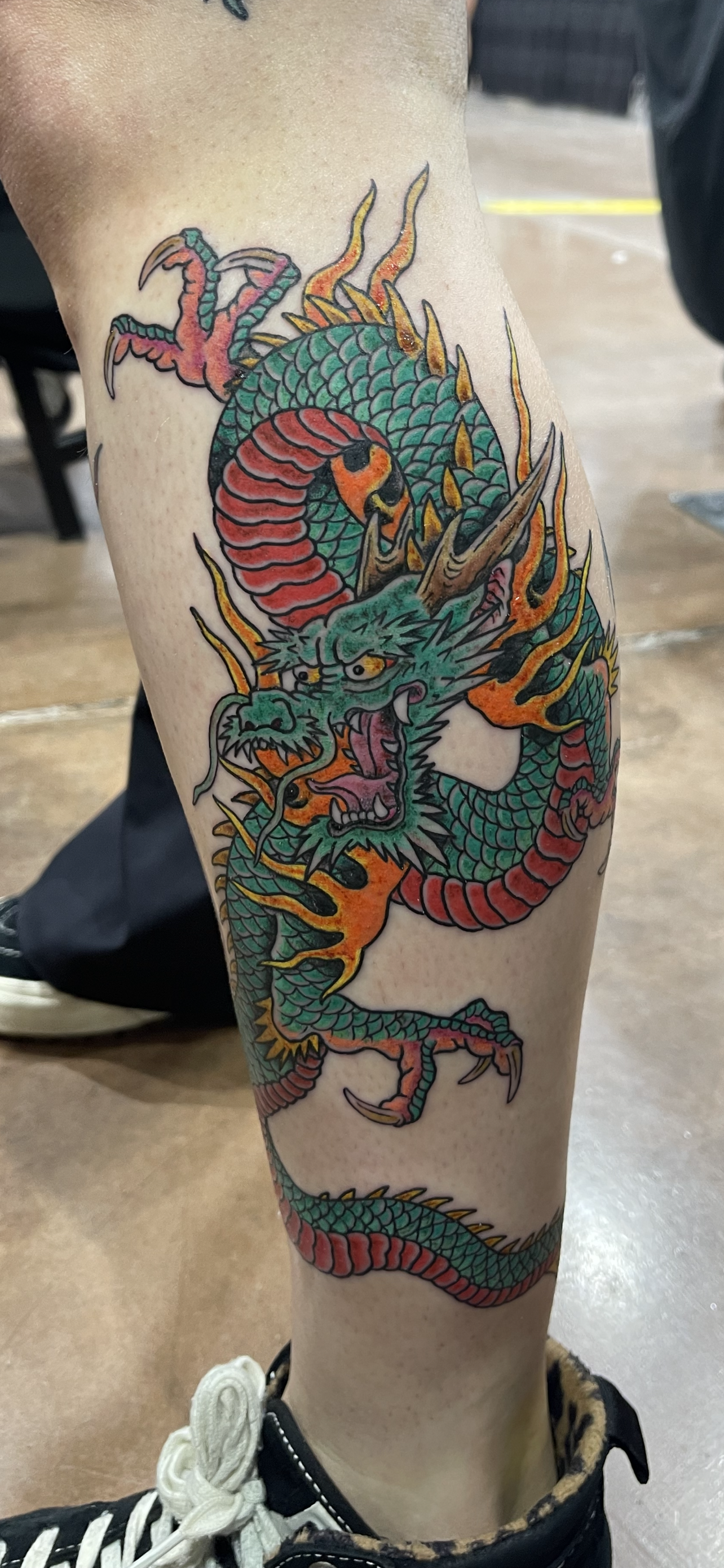 Colorful traditional Asian dragon tattoo on person's leg.