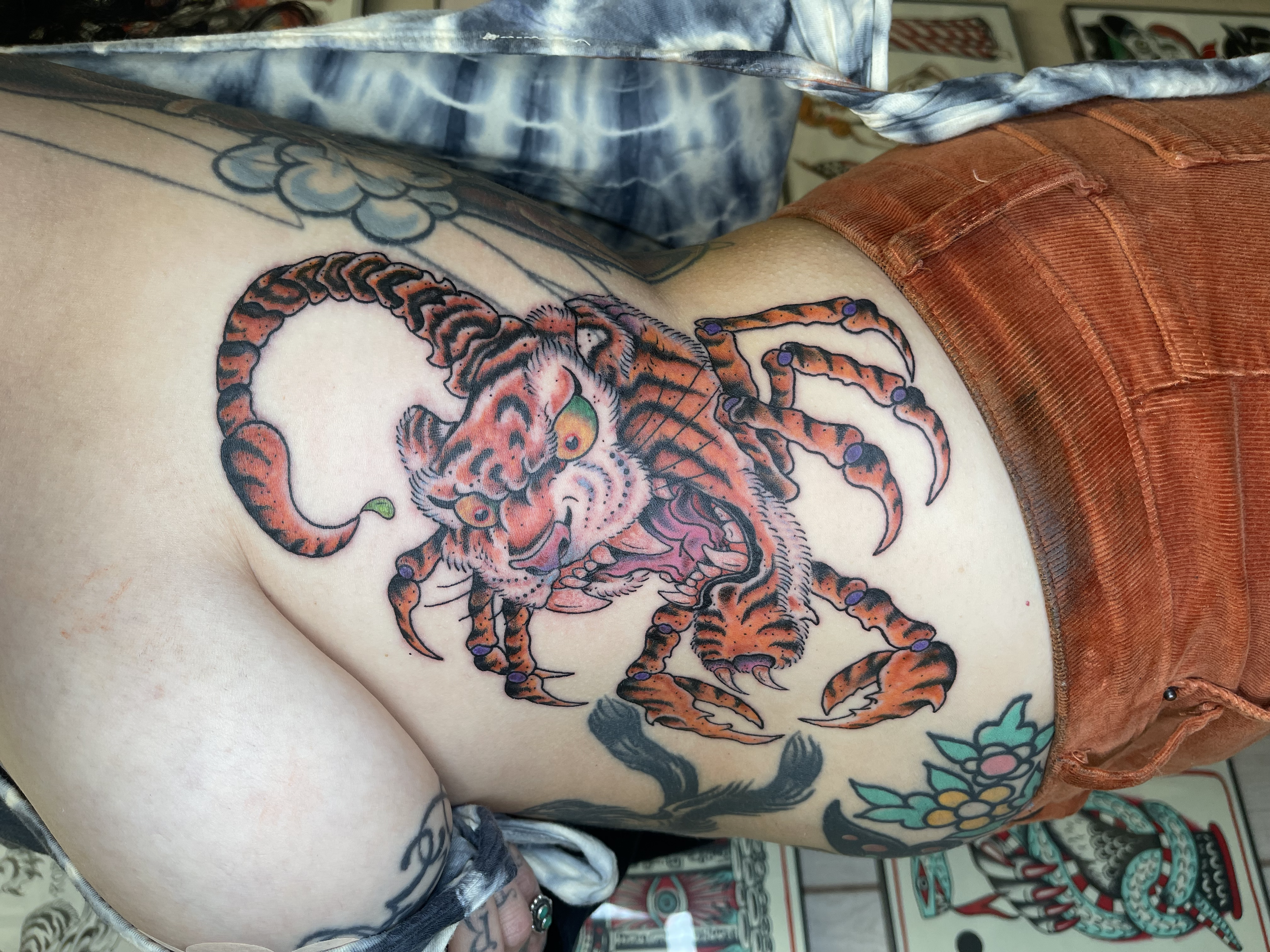Colorful tattoo of a tiger on a person's side and part of a tattoo of a black panther or similar large feline.