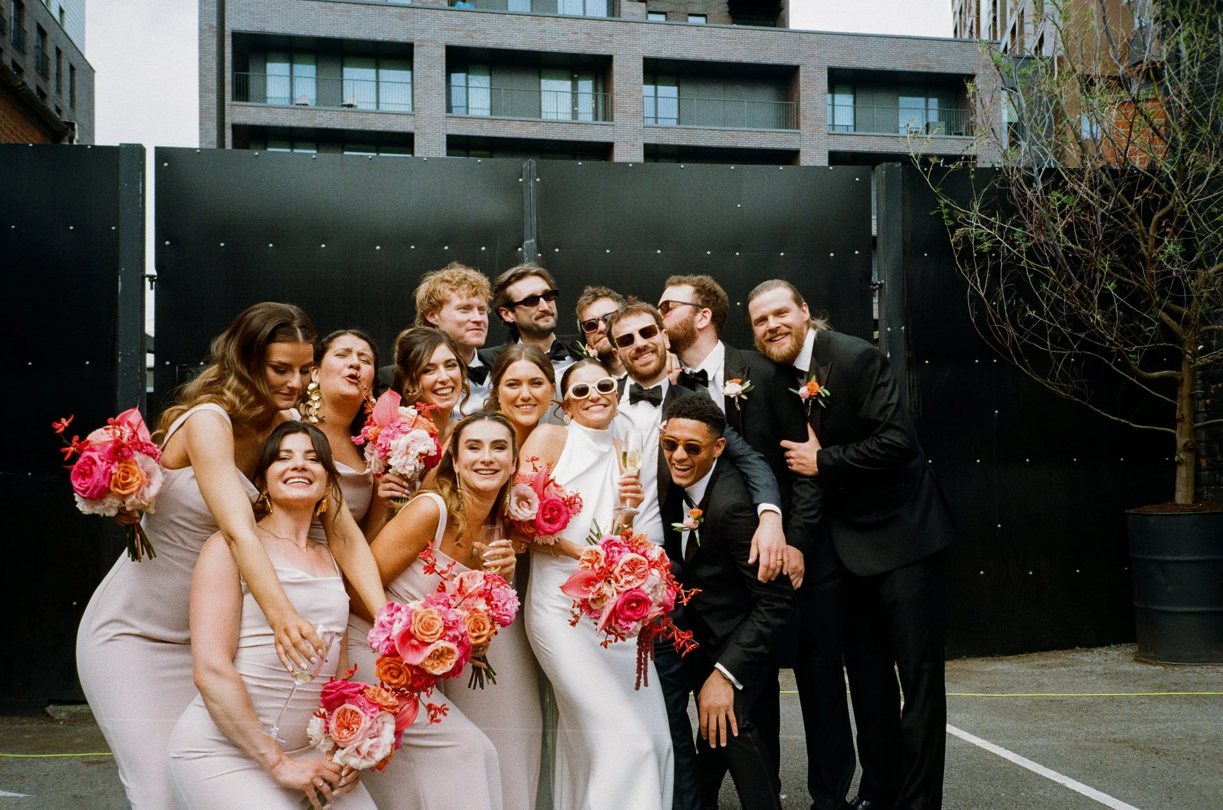 Melissa+&+Jacob+sharing+a+joyful+bridal+party+moment+at+Kimpton+Clocktower+Hotel+Manchester,+surrounded+by+their+closest+friends.