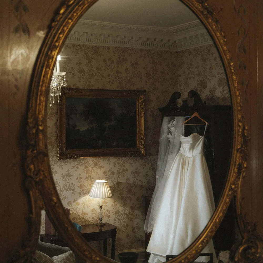 Bride’s wedding dress hanging in soft light at Merchant Taylors’ Hall