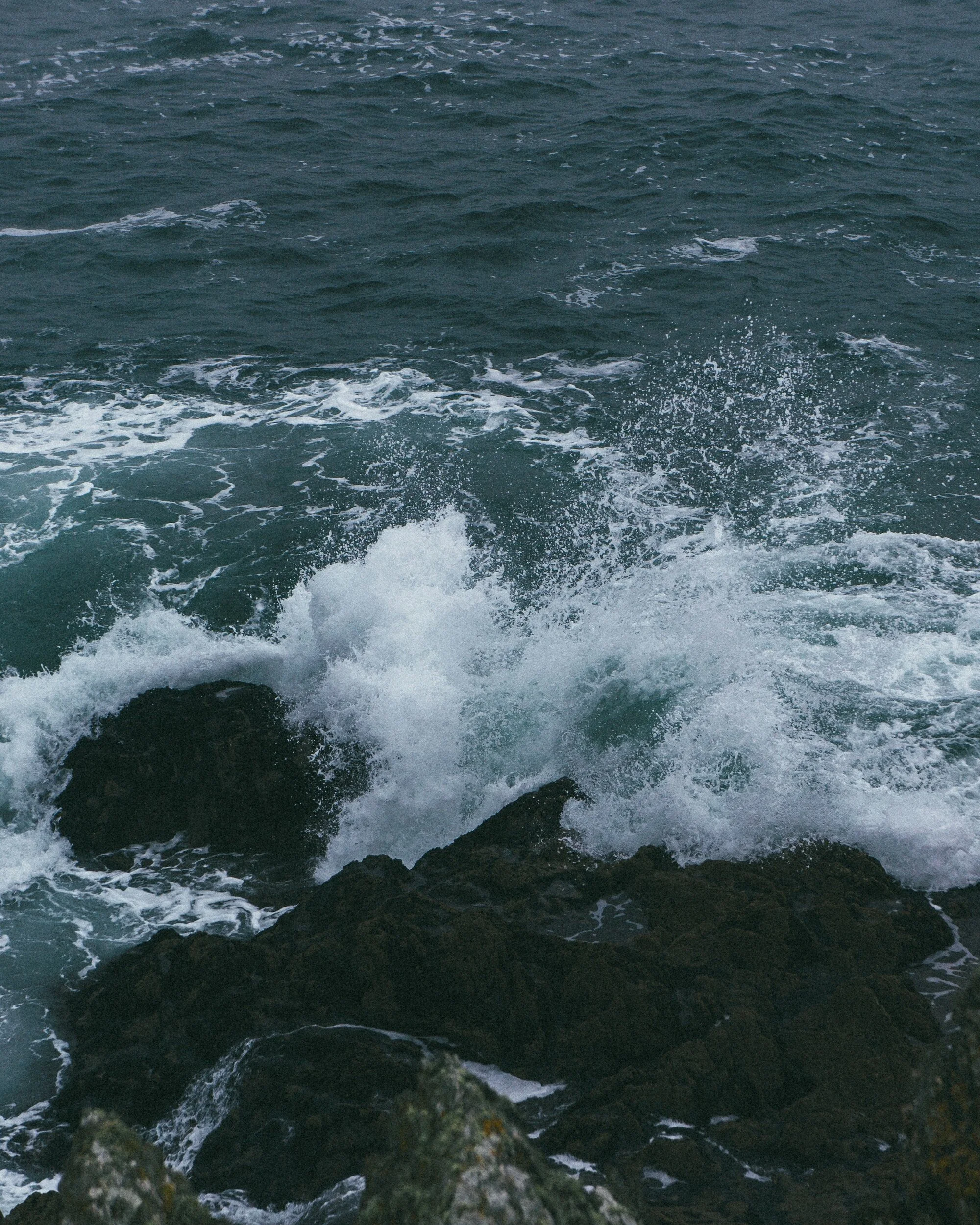 Waves crashing against dark rocks in the ocean