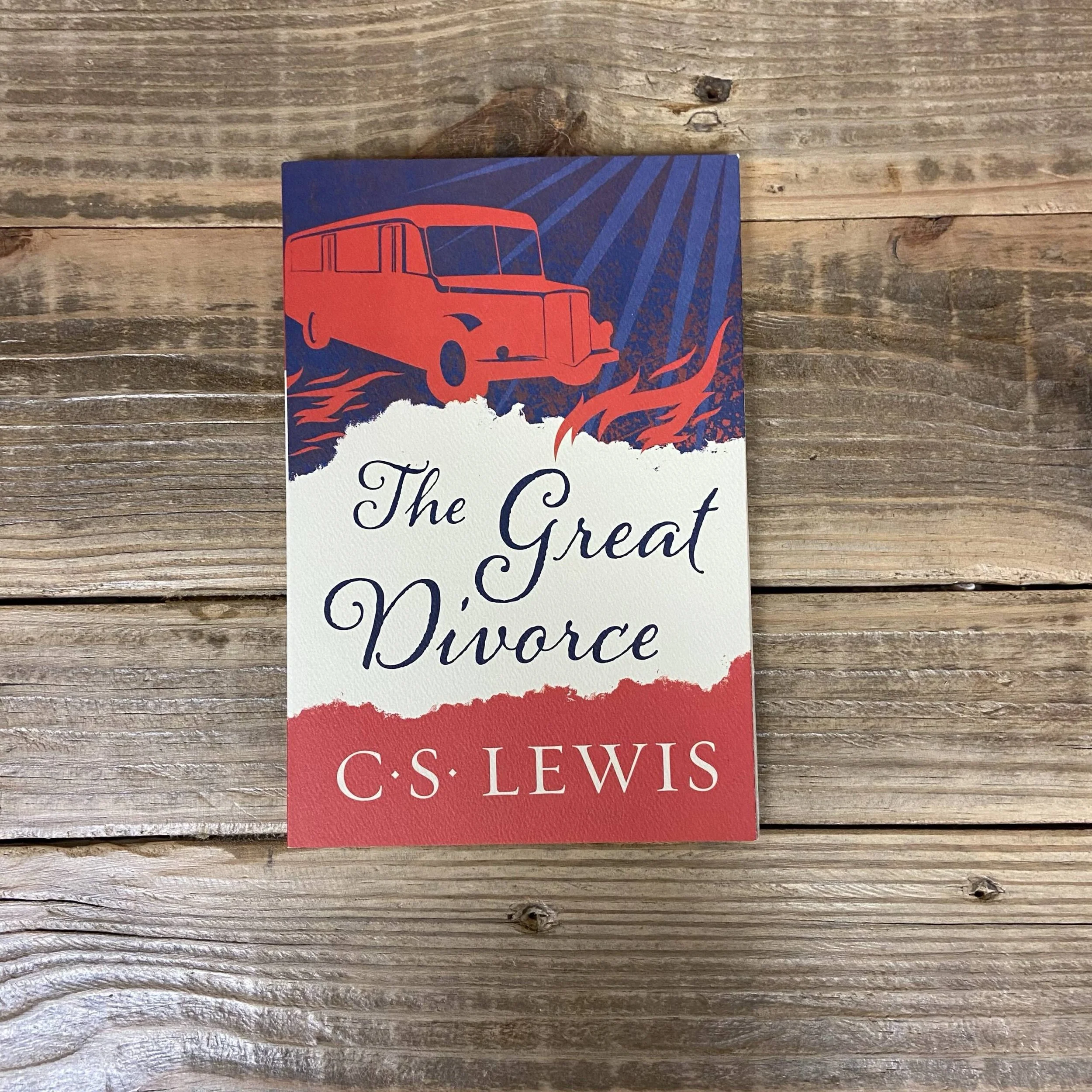 Book titled "The Great Divorce" by C.S. Lewis with a red vintage bus illustration on the cover, placed on a wooden surface.