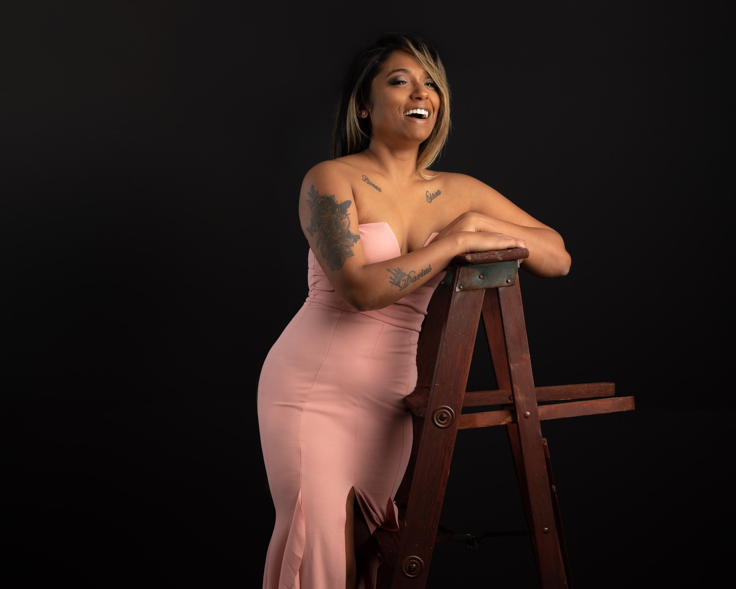 Beautiful Portrait of a woman on a ladder with a pink sleeveless dress smiling and enjoying her portrait session