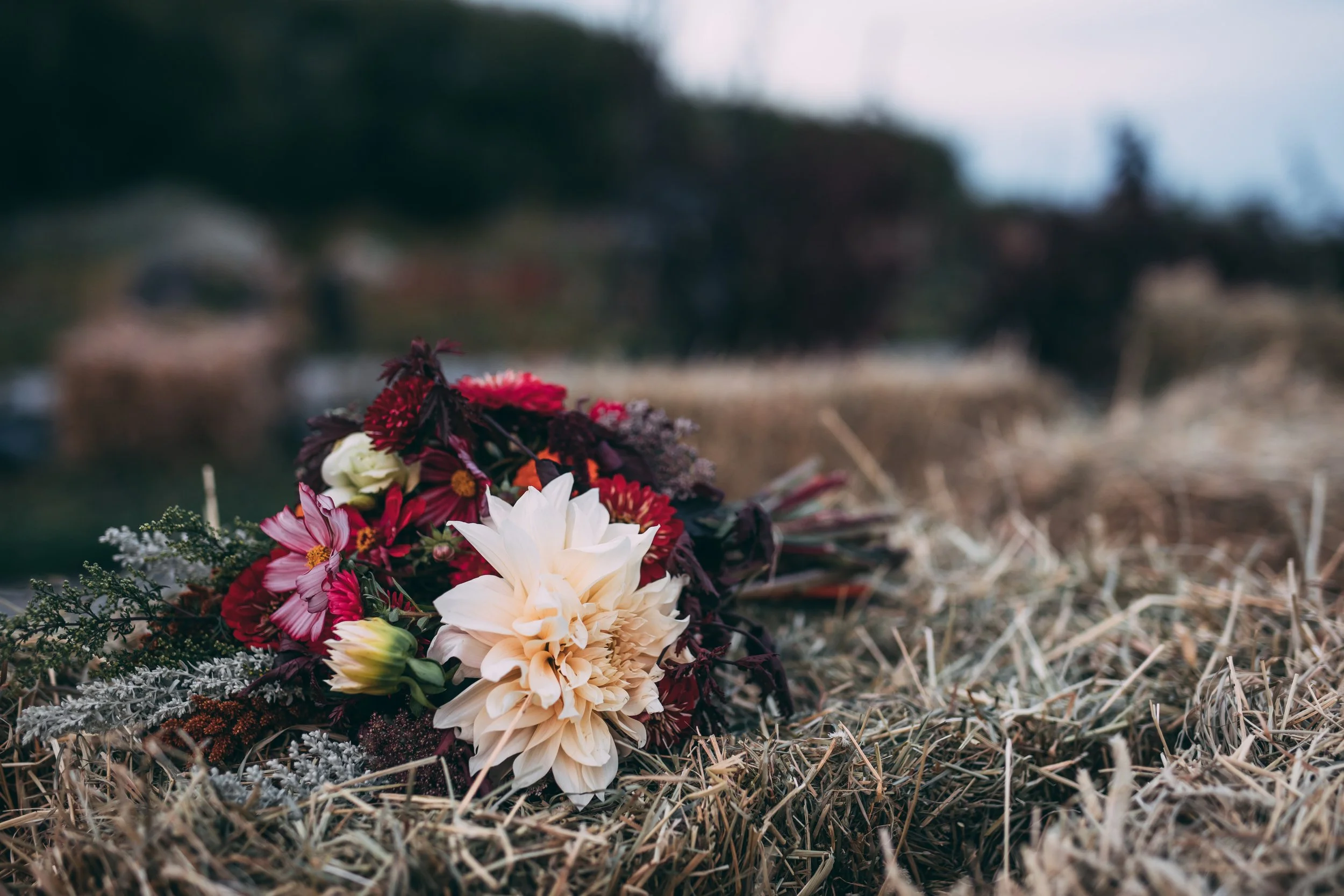A funeral wreath with white, pink, and purple flowers placed on a grassy surface.