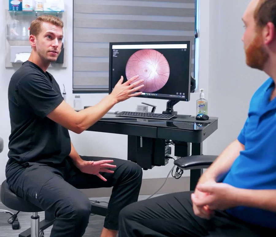 Doctor explaining eye exam results to patient in a medical office in Redding, CA, with a retina scan displayed on a computer monitor