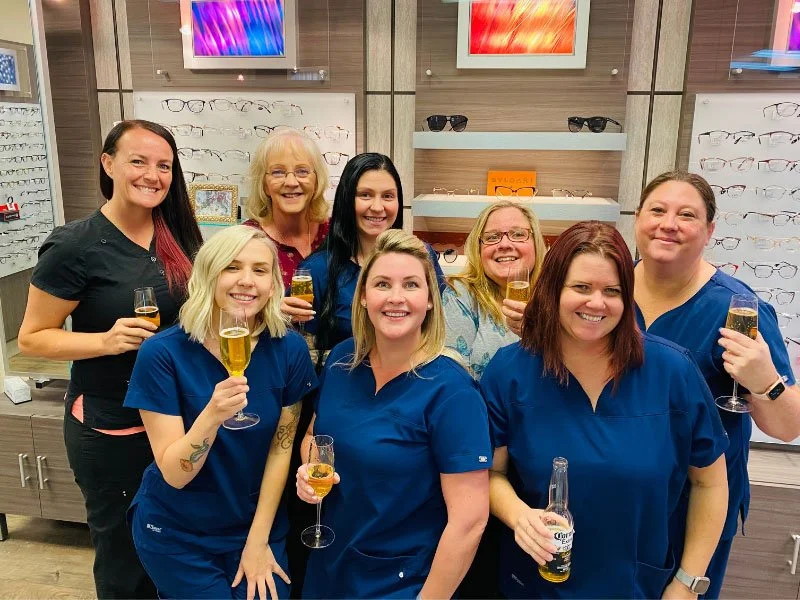 Group of women with glasses of champagne or wine in eyewear store.