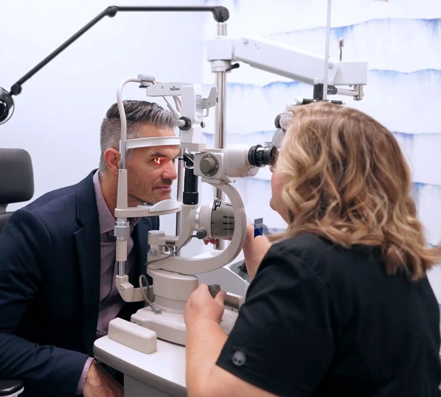 A man getting an eye exam using a slit lamp at an optometrist's office with a female eye care professional in Redding, CA