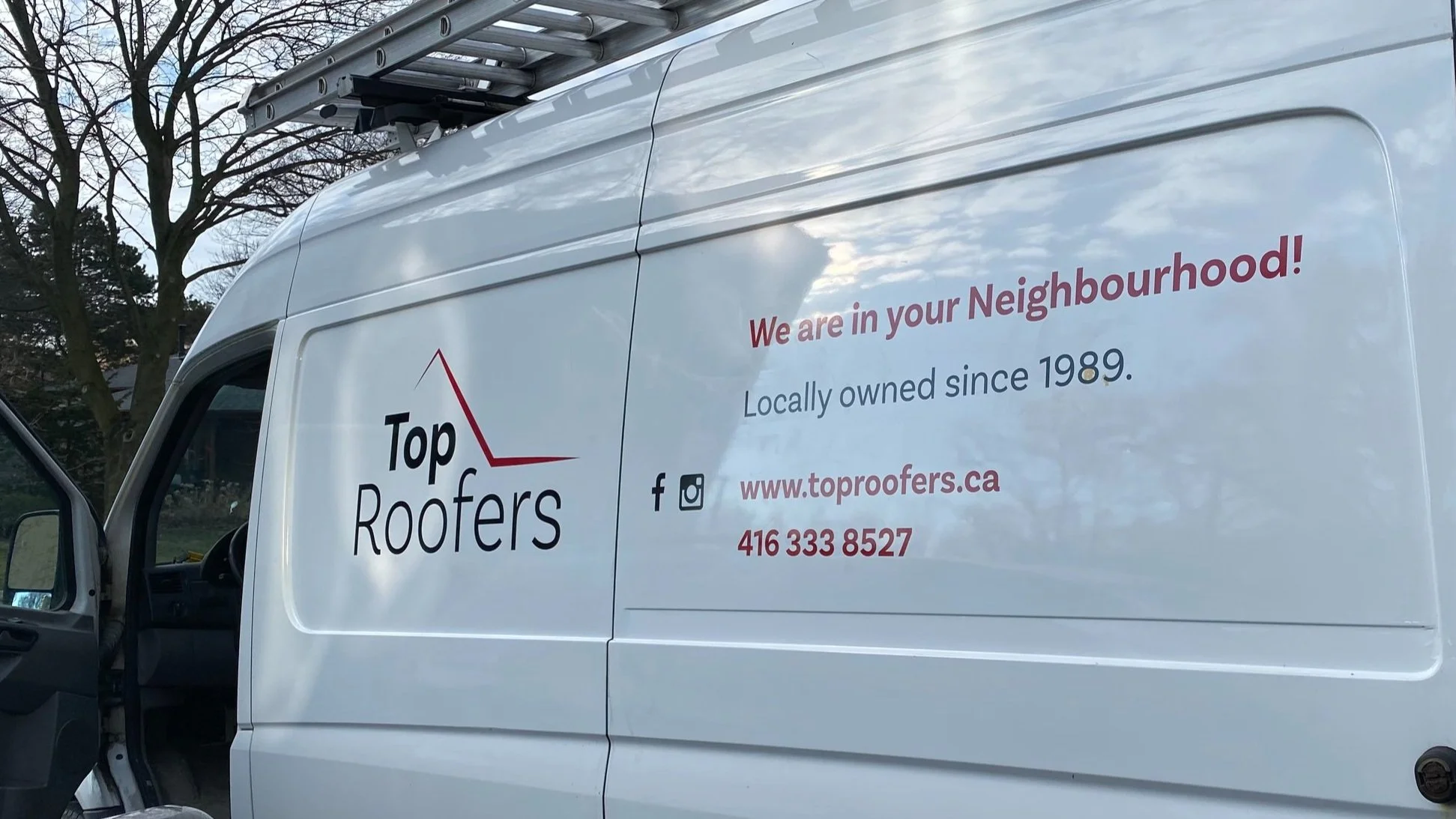 White company van with a roof ladder on top, advertising Top Roofers, a roofing company, with text indicating they are locally owned since 1989, and providing contact information including a website, phone number, and social media icons.