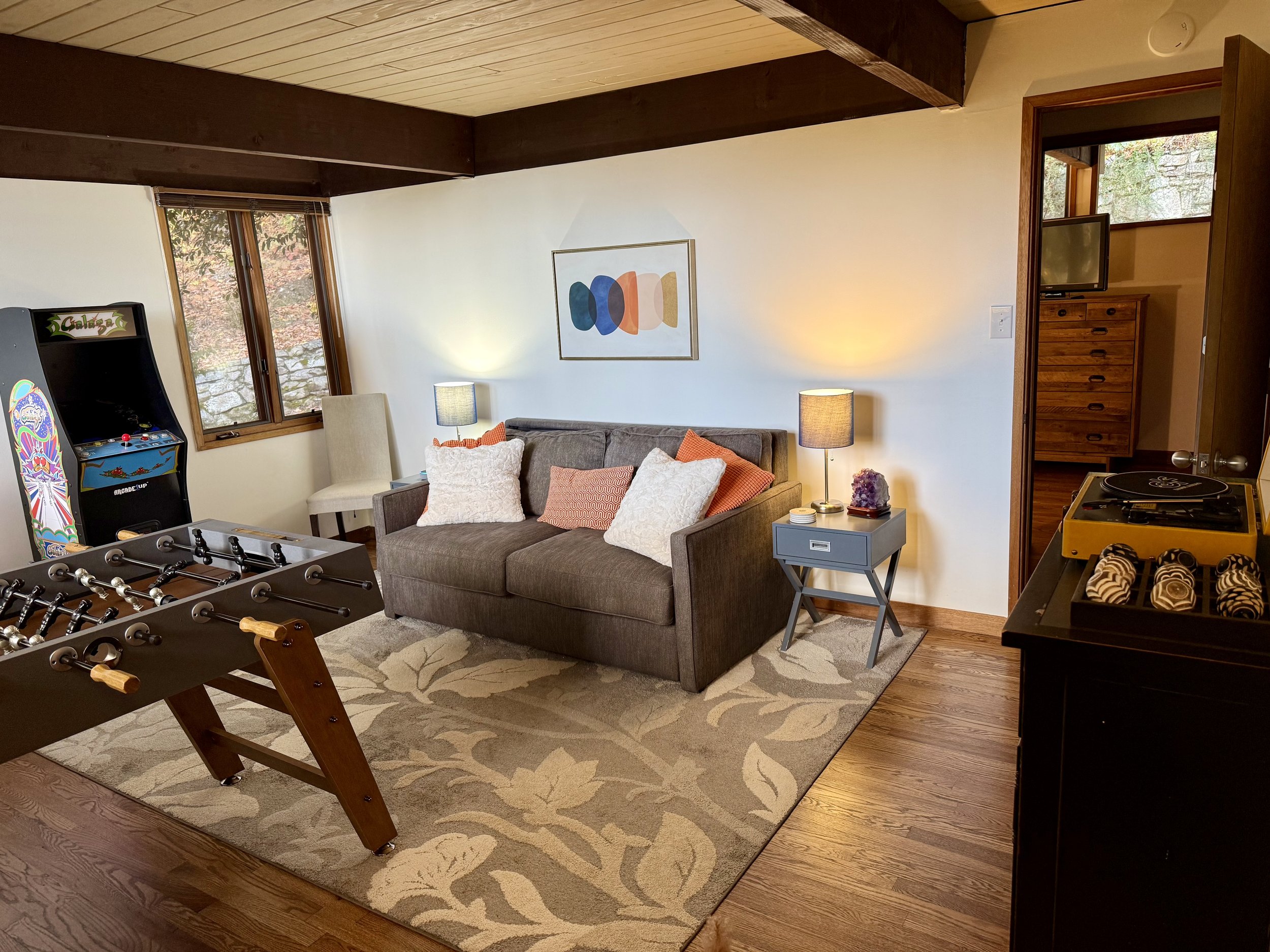 Game room lounge area with queen sleeper sofa and retro arcade games