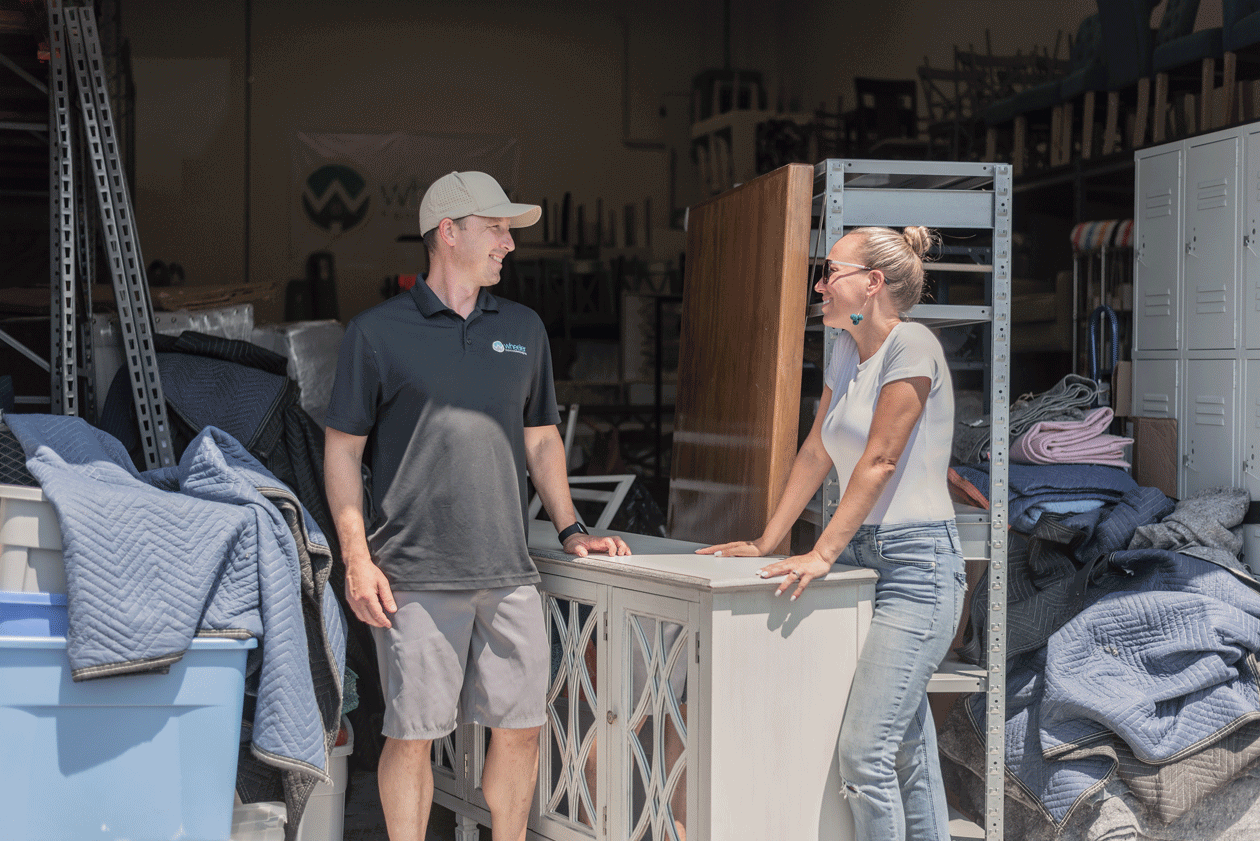 Josh and Tara, owners of Wheeler Home Concepts, discussing real estate marketing and staging in their warehouse