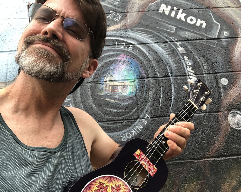 Derek Goodwin with ukulele by Nikon camera mural