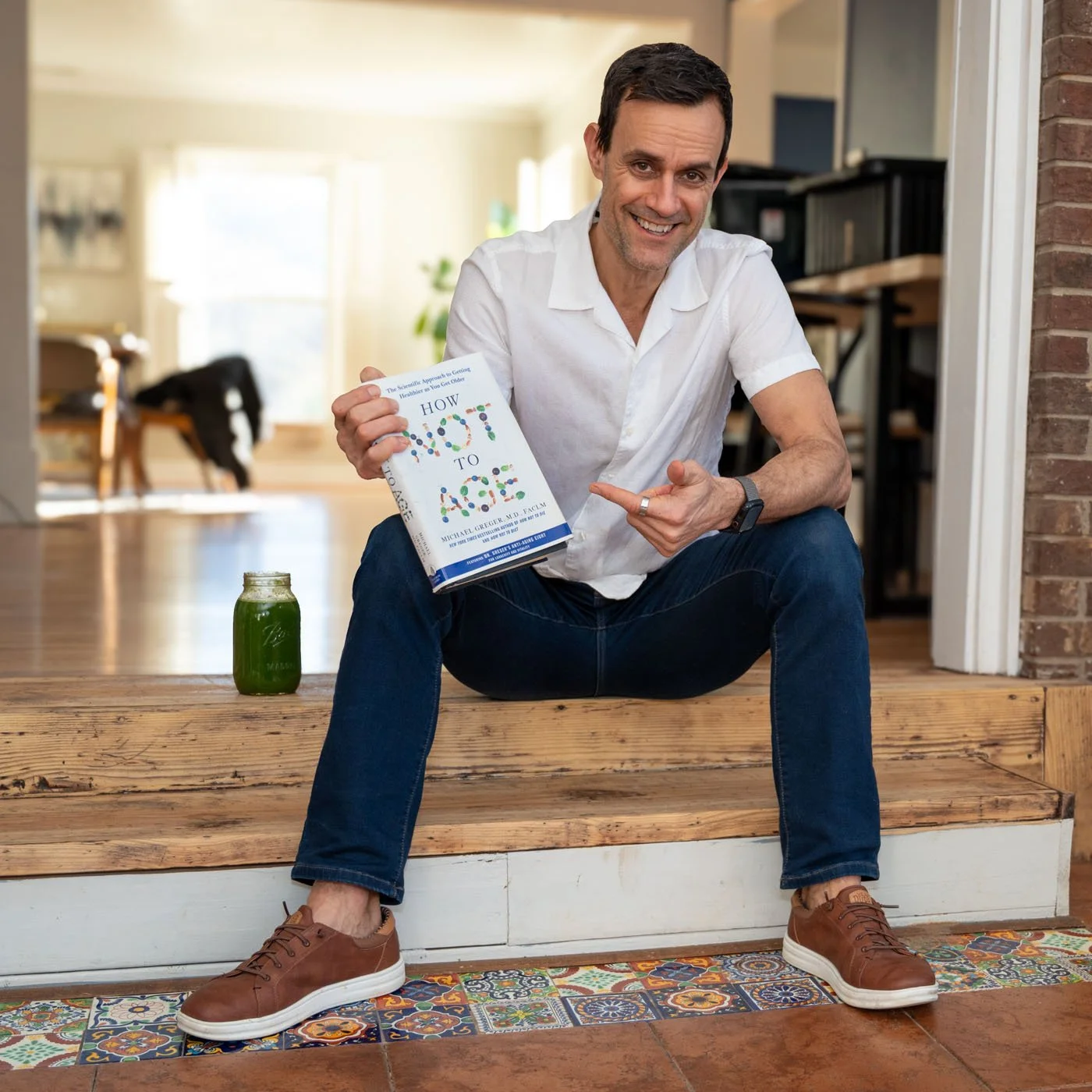 Travis Richardson of Be Well Asheville at home with a longevity book "How not to Age" by Michael Greger MD
