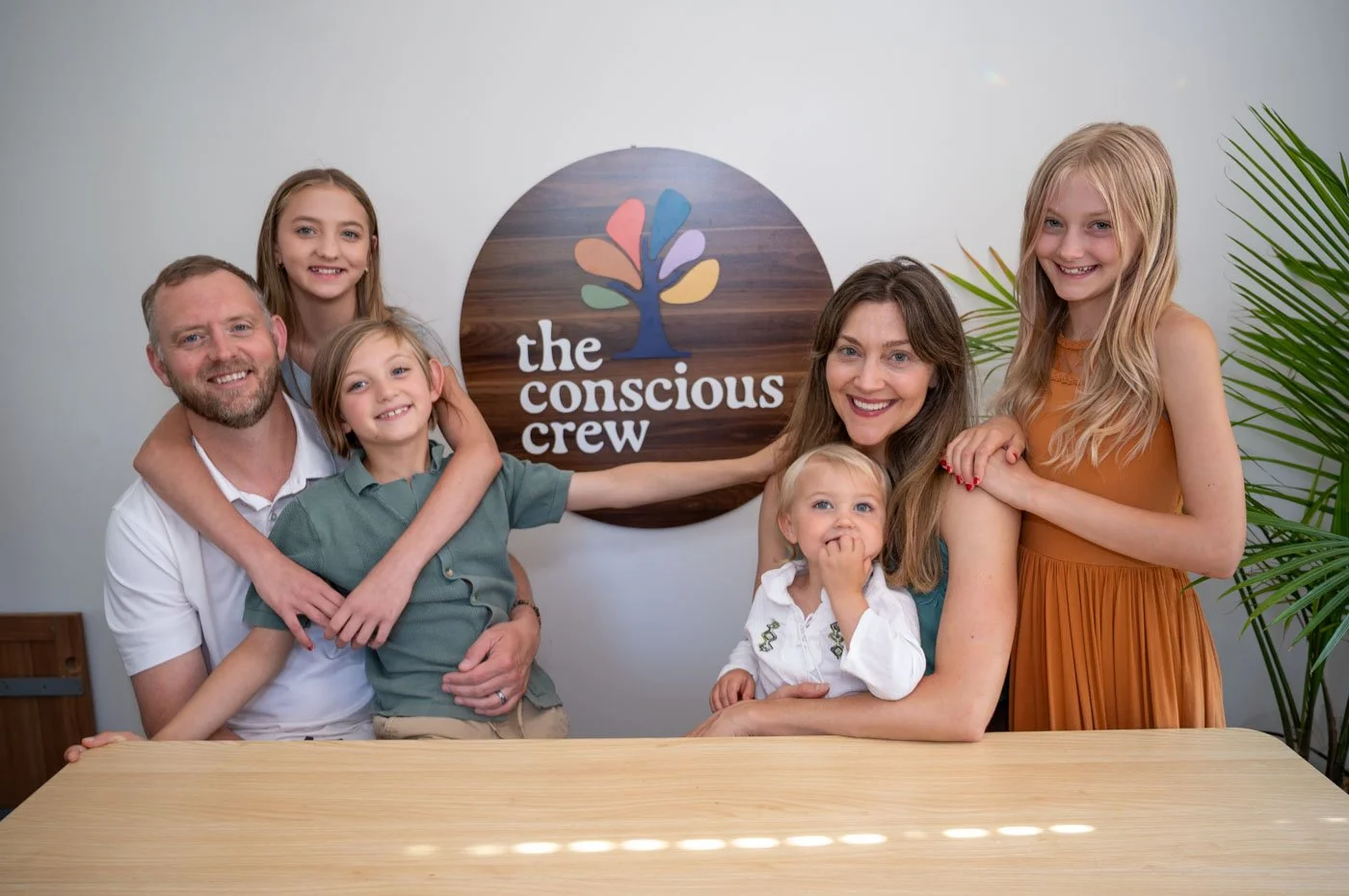 Stephanie, Ryan, and their four kids with The Conscious Crew logo. The youngest was still deciding how he felt about the camera.