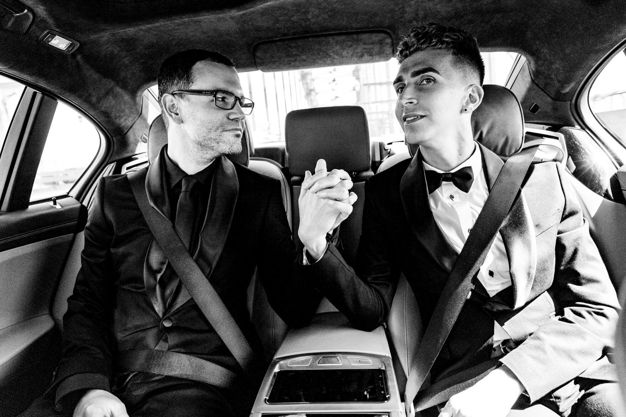 same sex wedding of two grooms in a car holding hands
