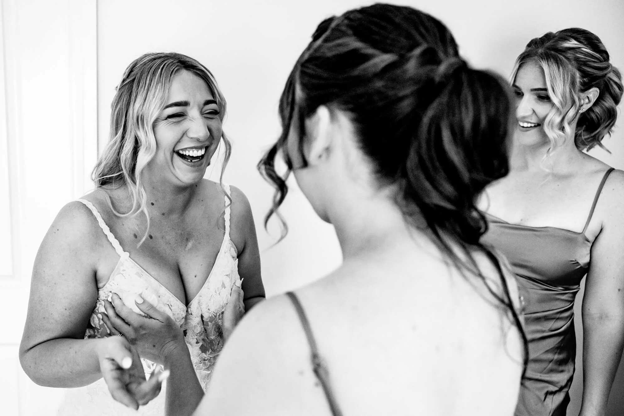 Bride and bridesmaid laughing and touching boobs