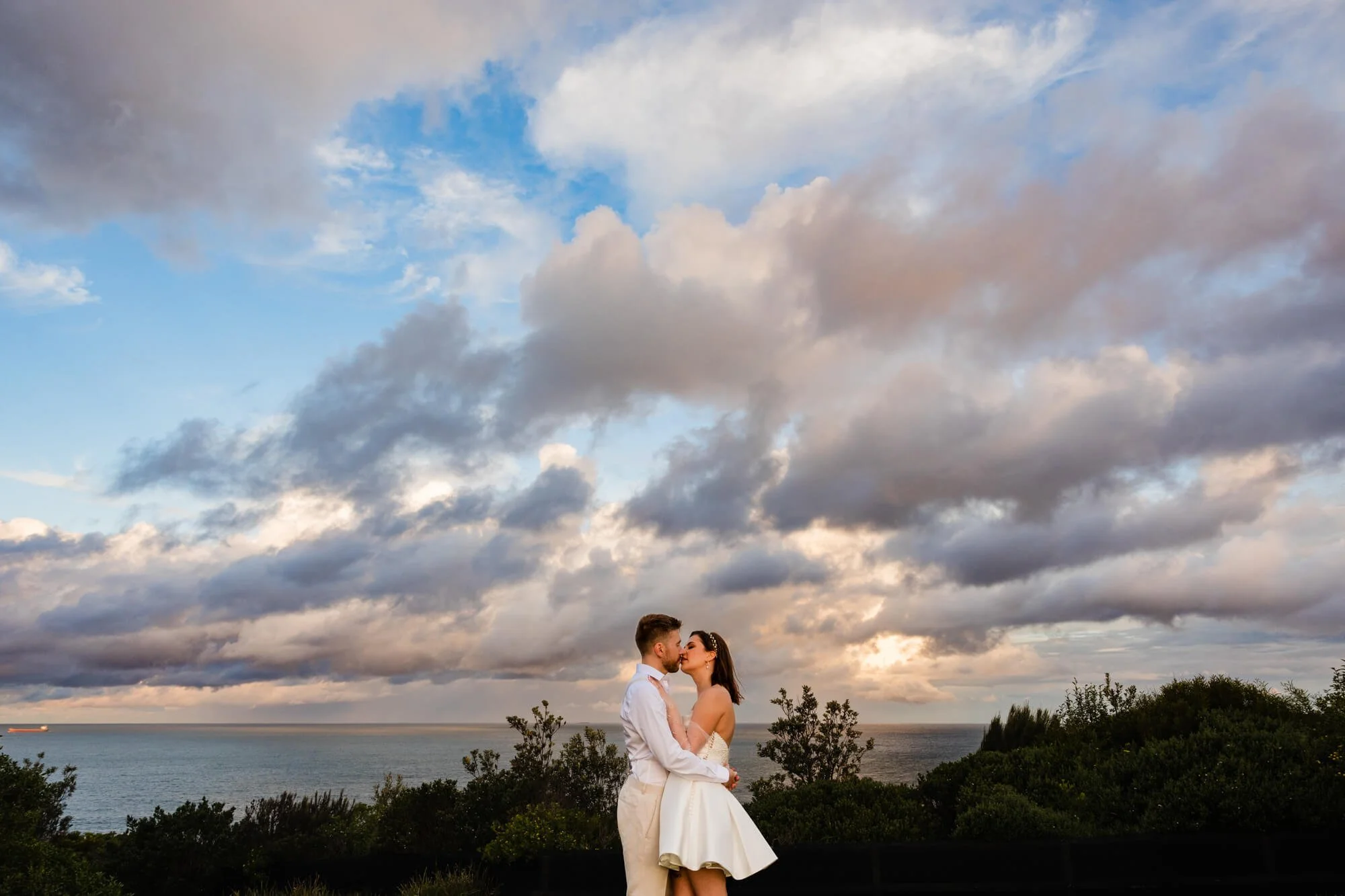 Bride and groom kissing in the clouds