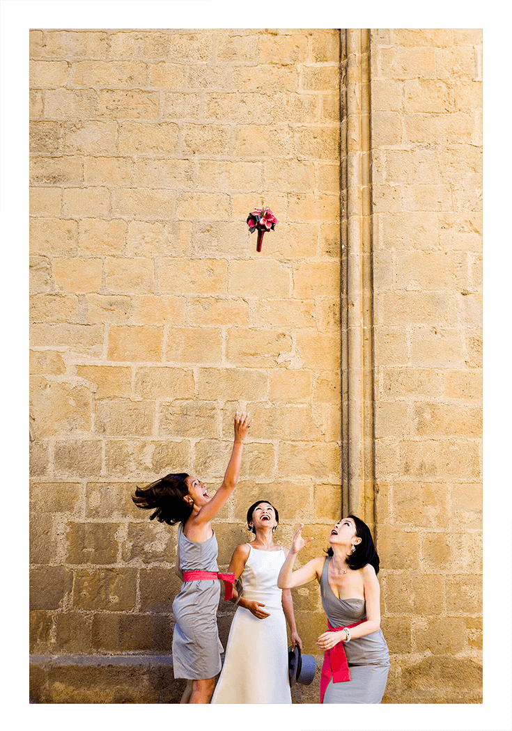 Two bridesmaids are jumping to catch the bride's bouquet as part of a wedding photography package