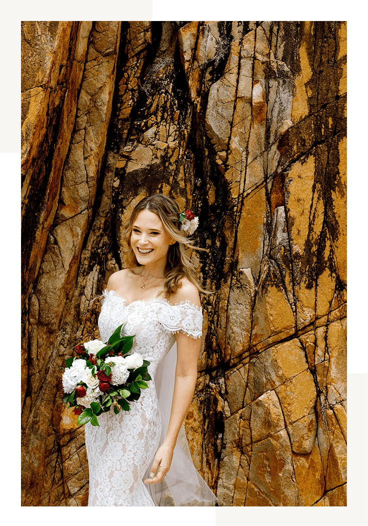Bride laughing in front of coastal rocks on Shoal bay Beach in Port Stephens