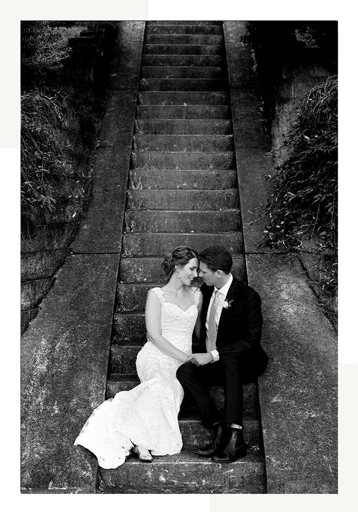 Black and white photography of a couple seating on stairs taken during their wedding photography package