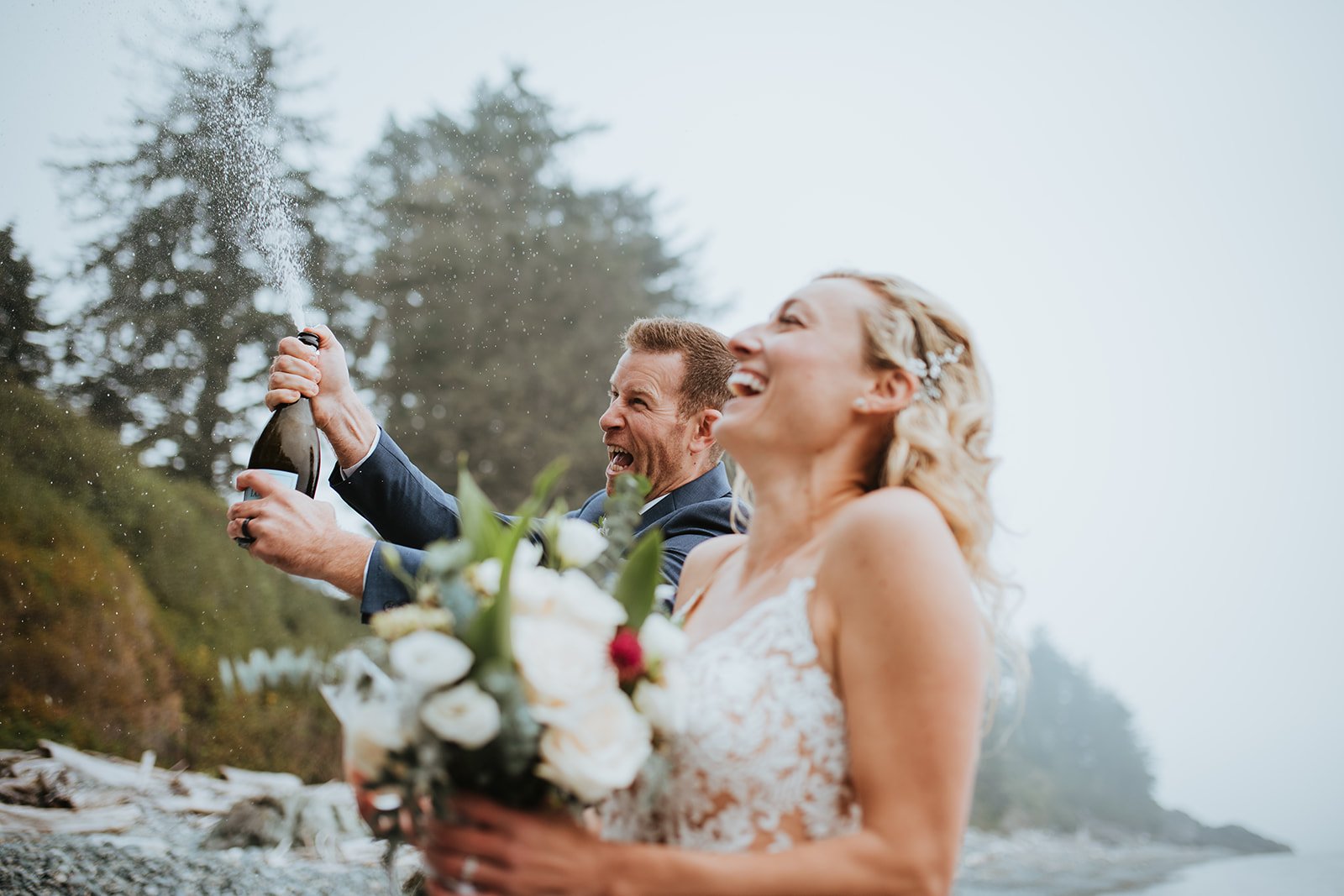 couple-popping-champagne-bottle-at-sooke-beach-for-their-elopement