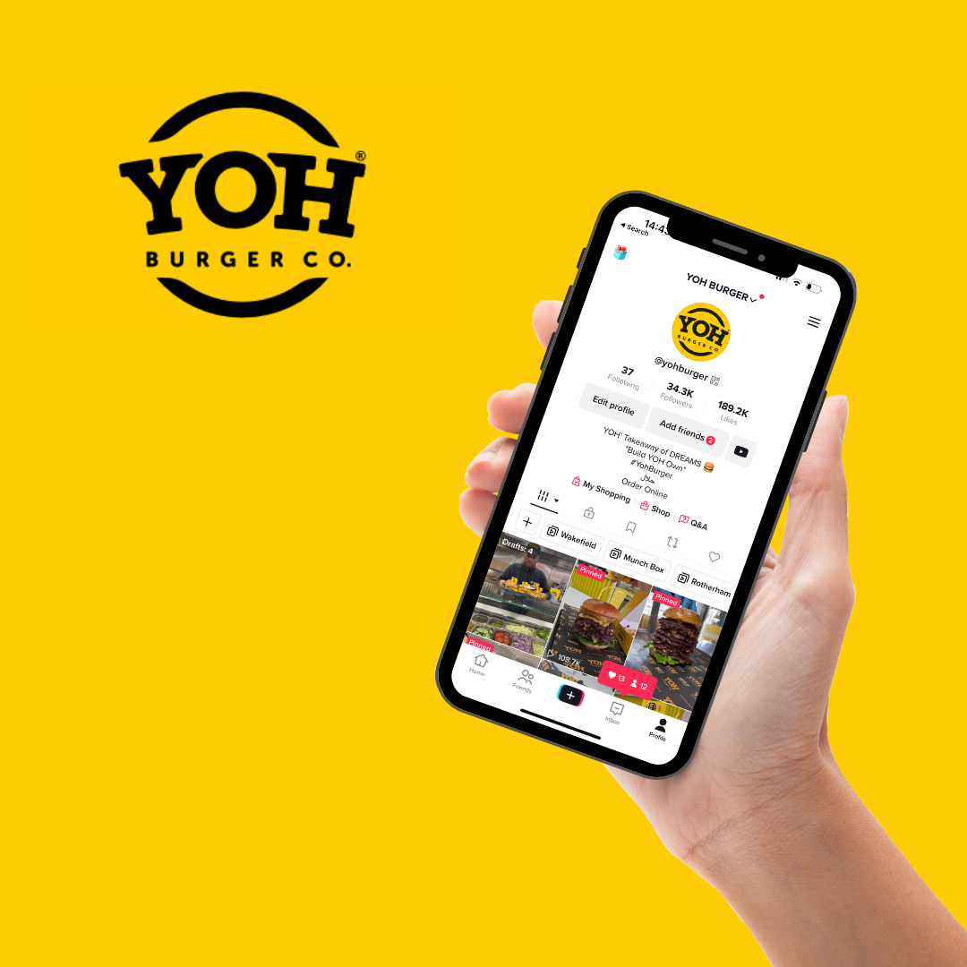 Hand holding a smartphone showing the TikTok profile of YOHvBURGERCO, a burger restaurant, against a yellow background with YOHvBURGERCO logo.