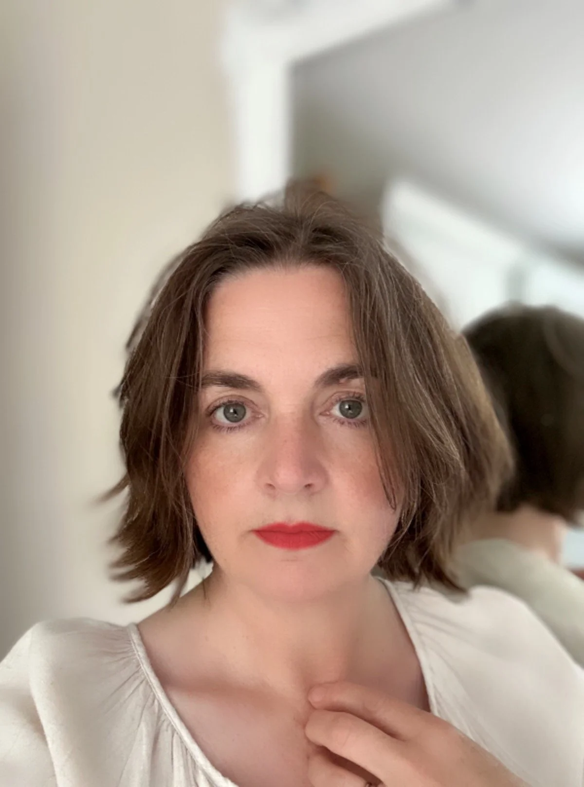 A woman with shoulder-length brown hair and red lipstick..