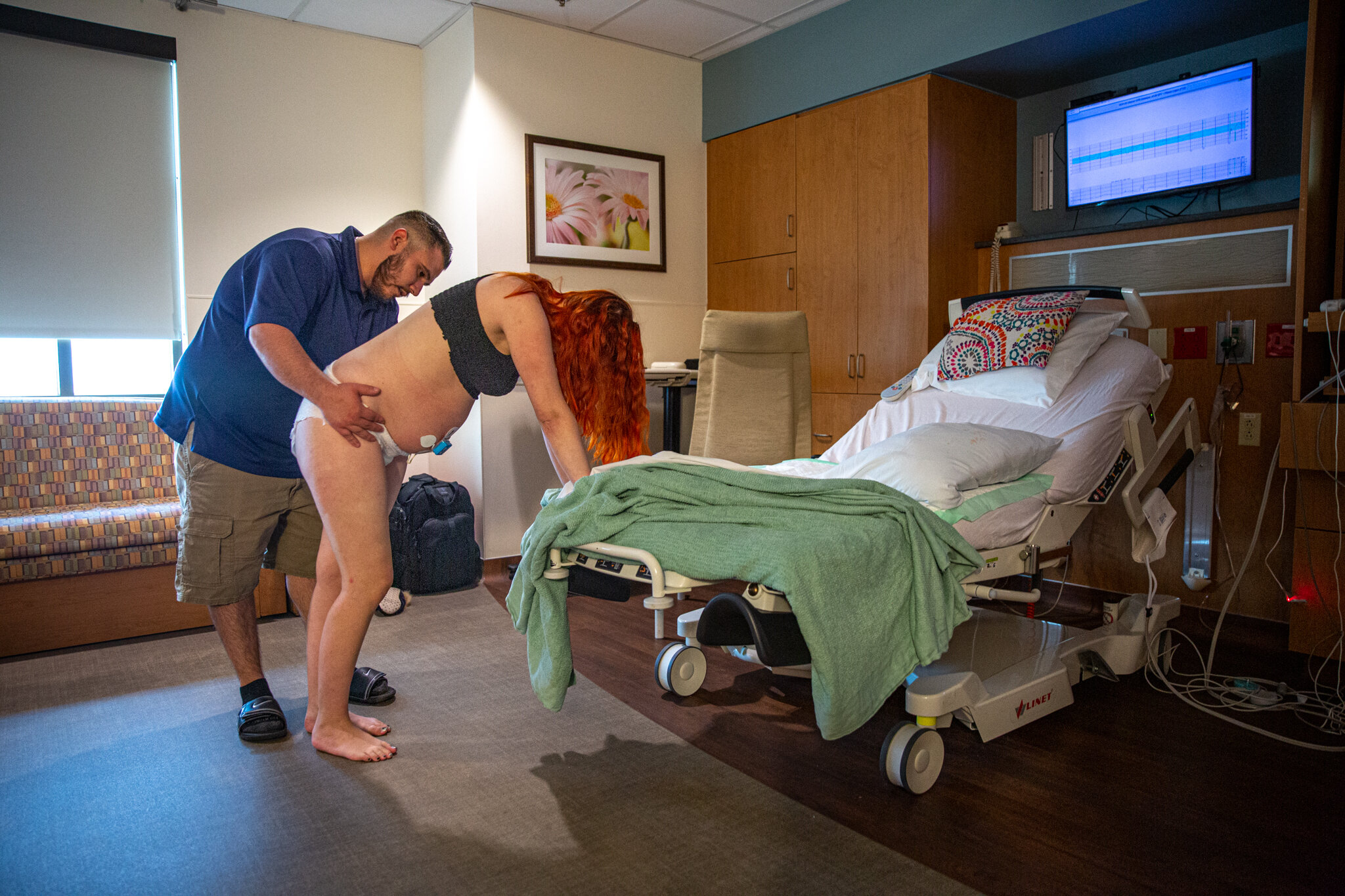 A man giving his laboring wife hip squeezes in a hospital room