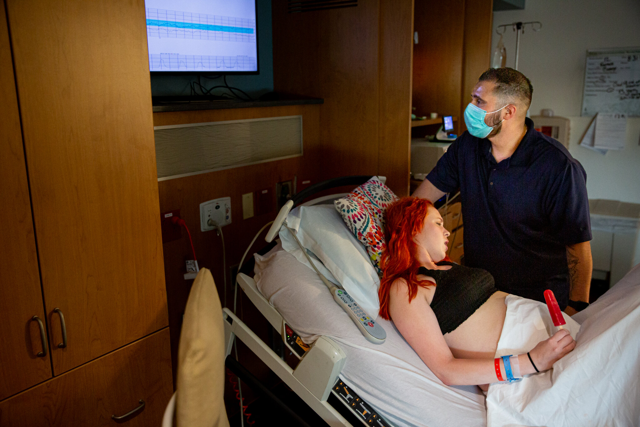 Woman in hospital bed going through contractions while her husband watches the monitors