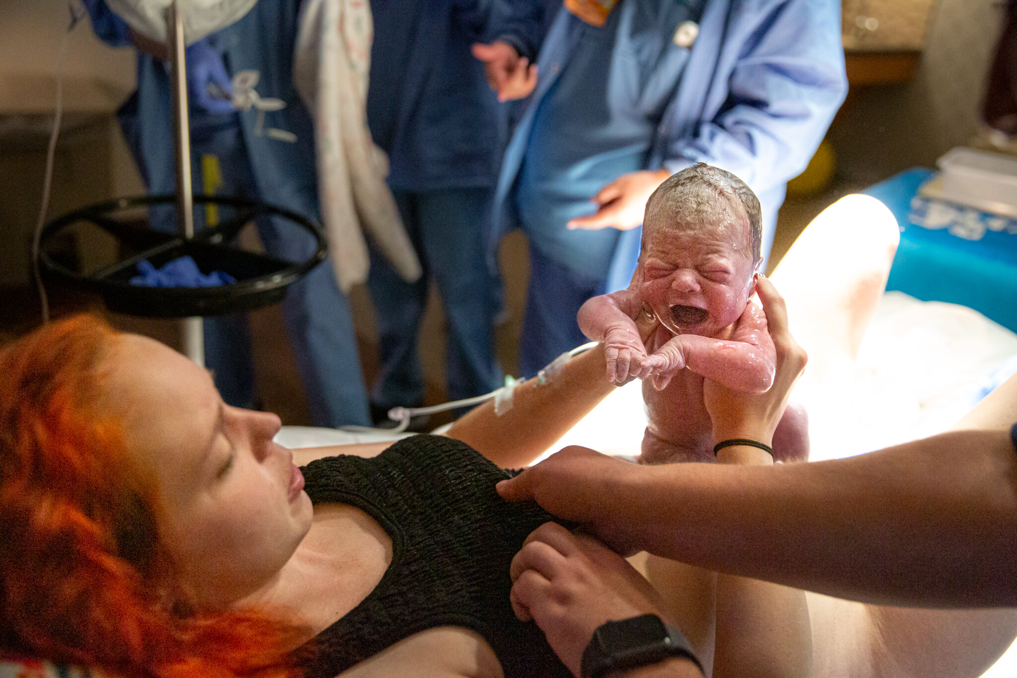 Woman pulling newborn baby to her chest