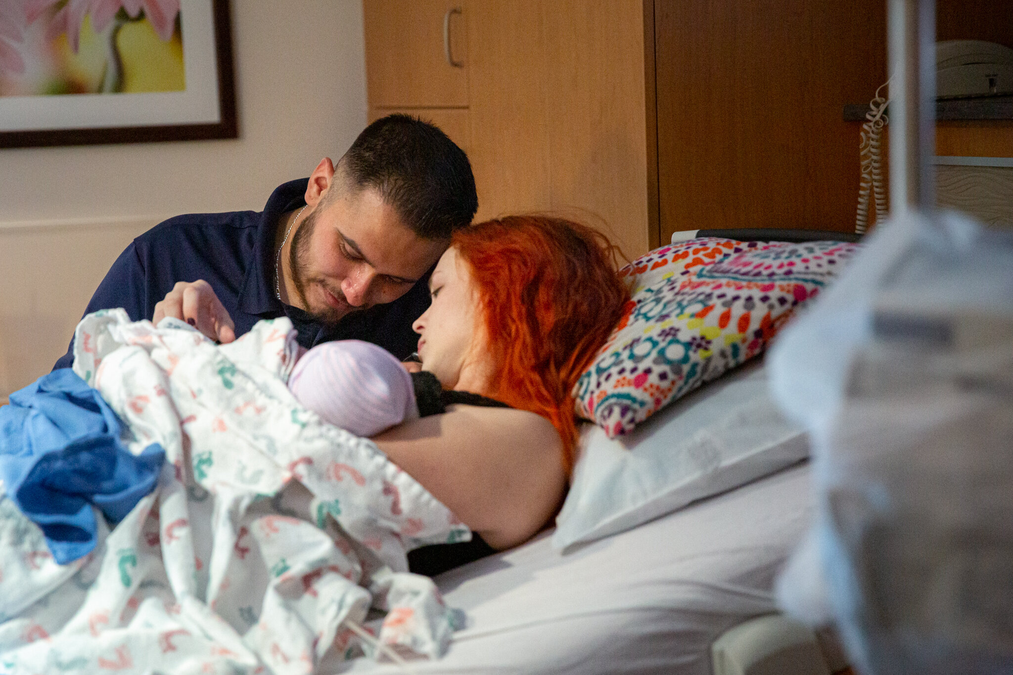 A couple with heir heads close looking at their newborn baby