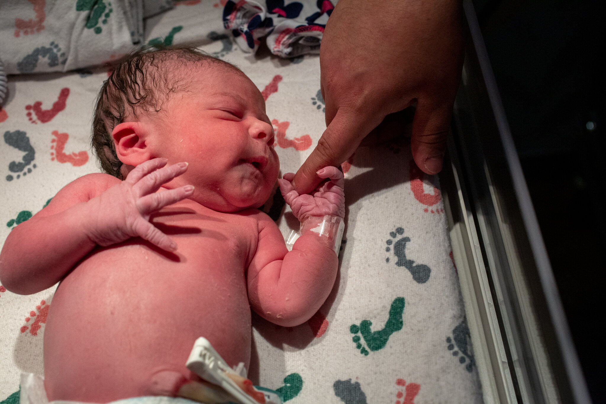 Newborn baby grasping dad's finger