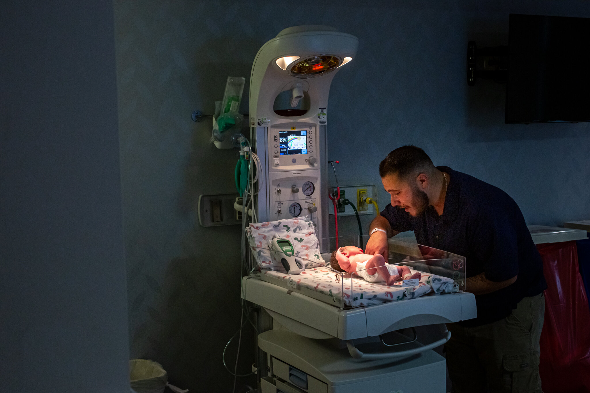 Dad speaking to newborn under hospital warmer