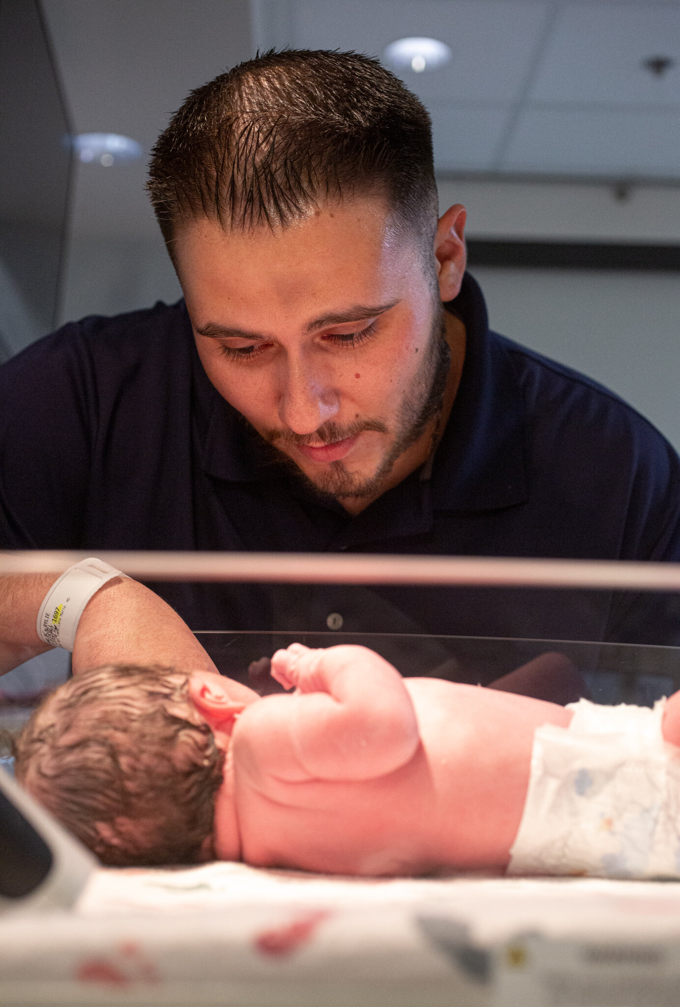 Dad looking at newborn in the hospital cradle