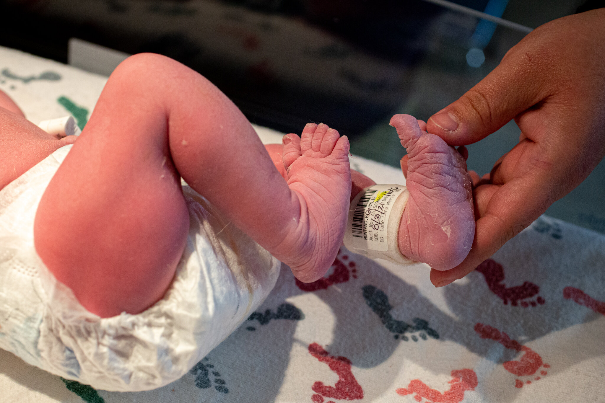 Dad holding one of a diapered baby's feet