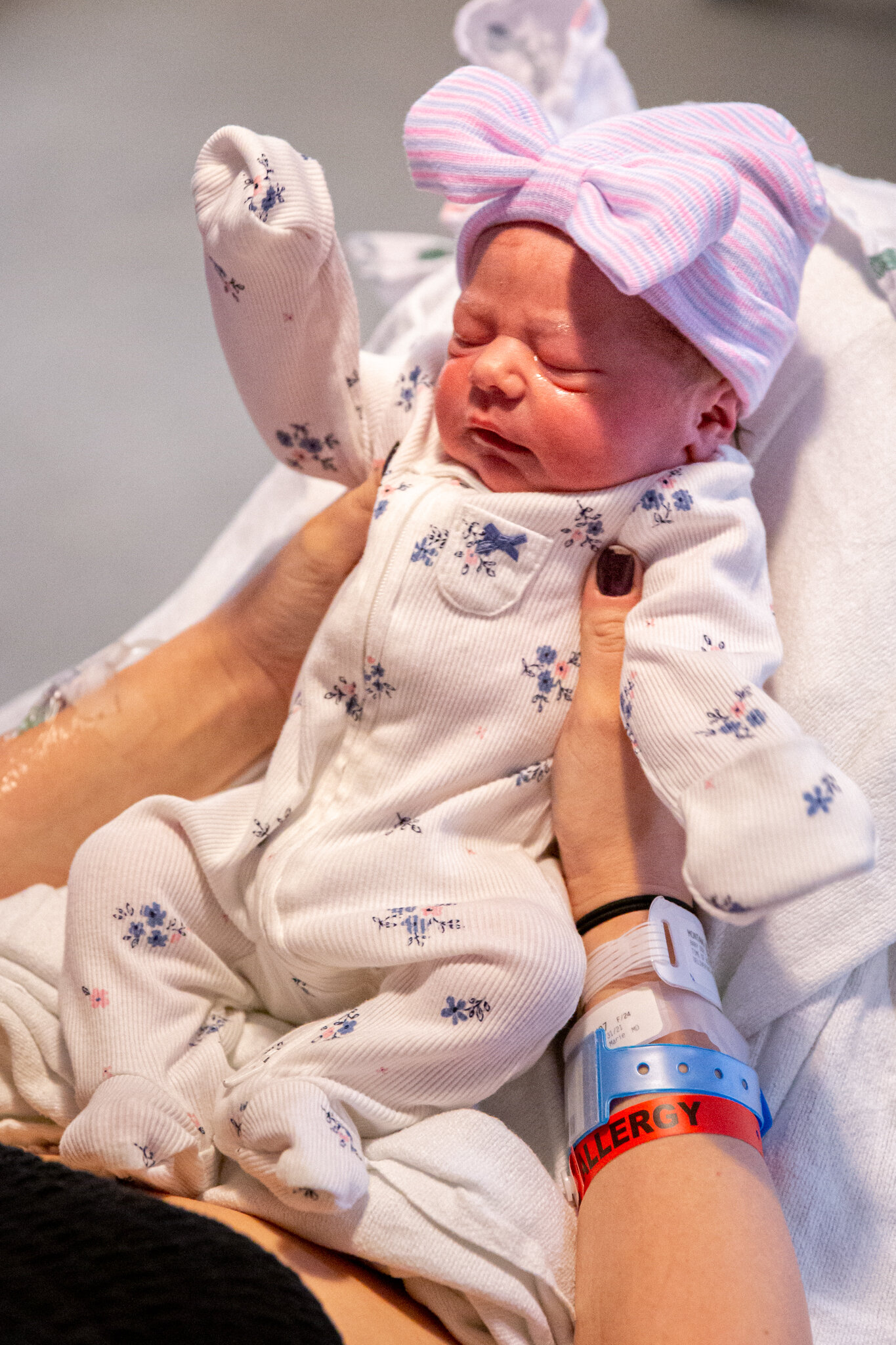 Baby in a onesie and hospital hat with bow