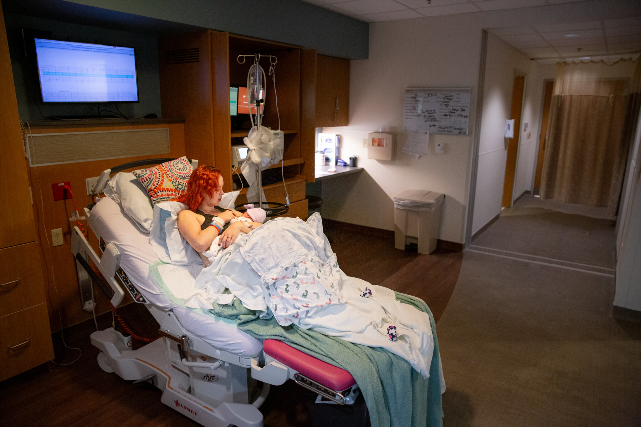 Woman in hospital bed cuddling her baby