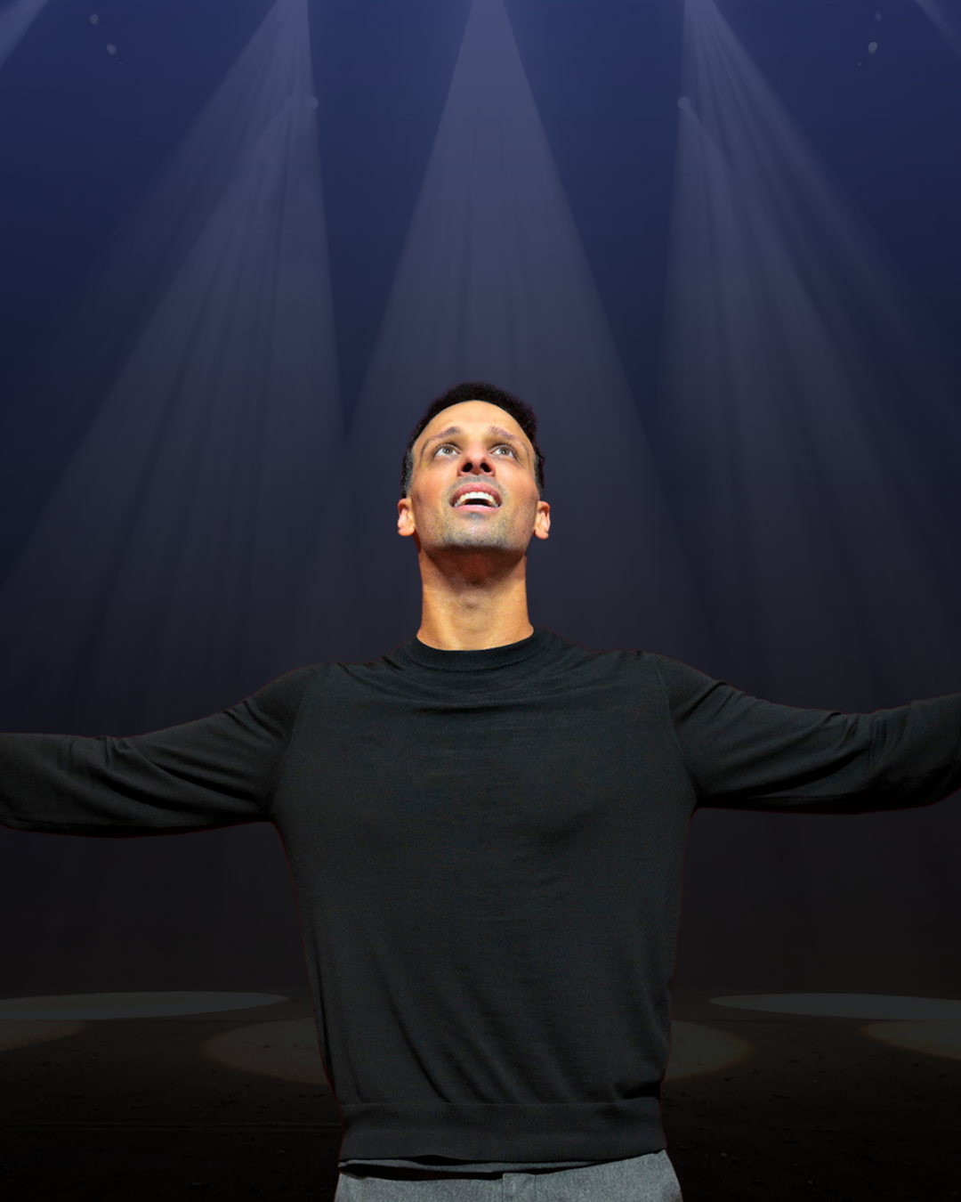 Ari'el Stachel in a black shirt looking up towards the stage lights.