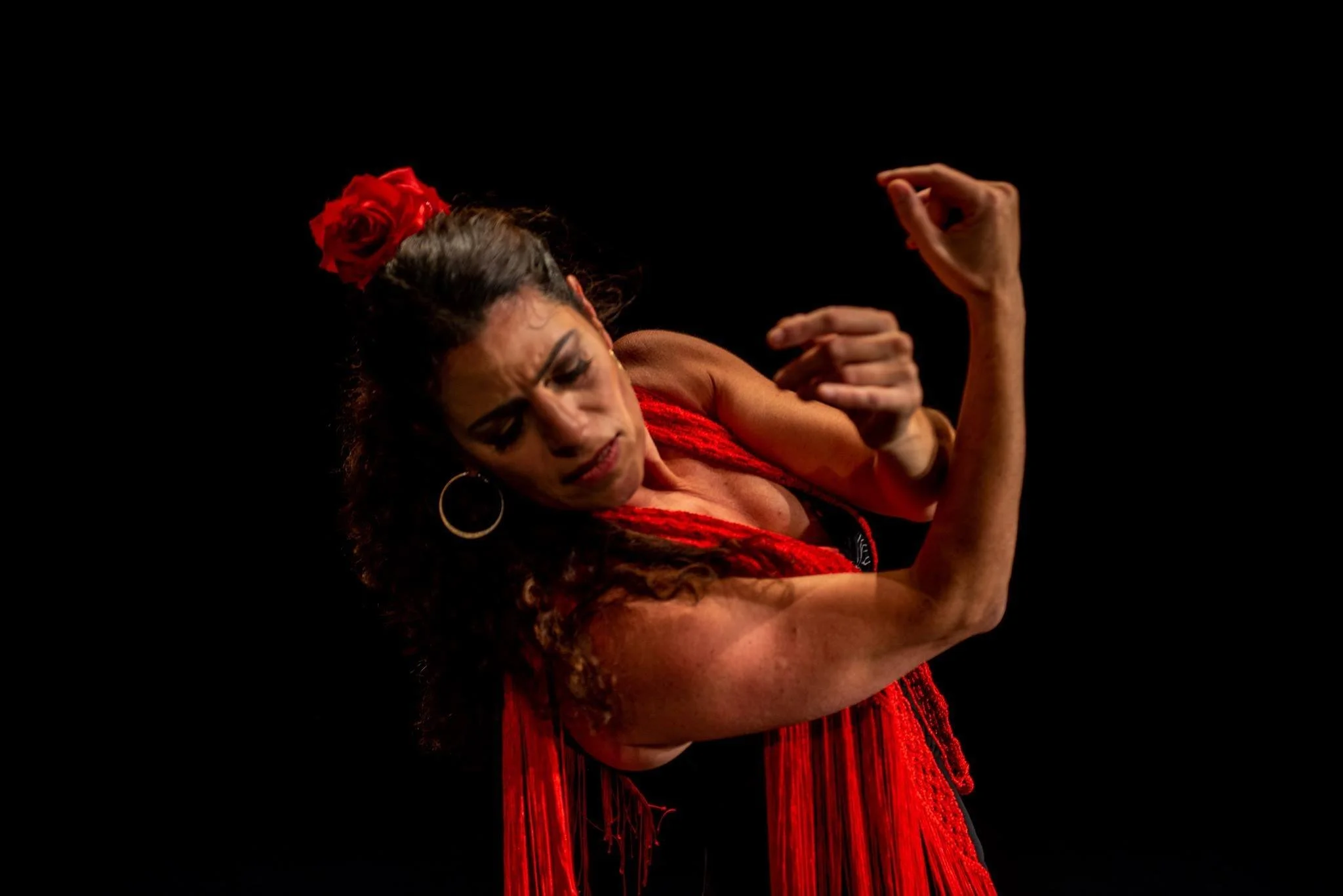 Liat Har Lev in a red dress with a red flower in her hair, in a sideways flamenco pose.