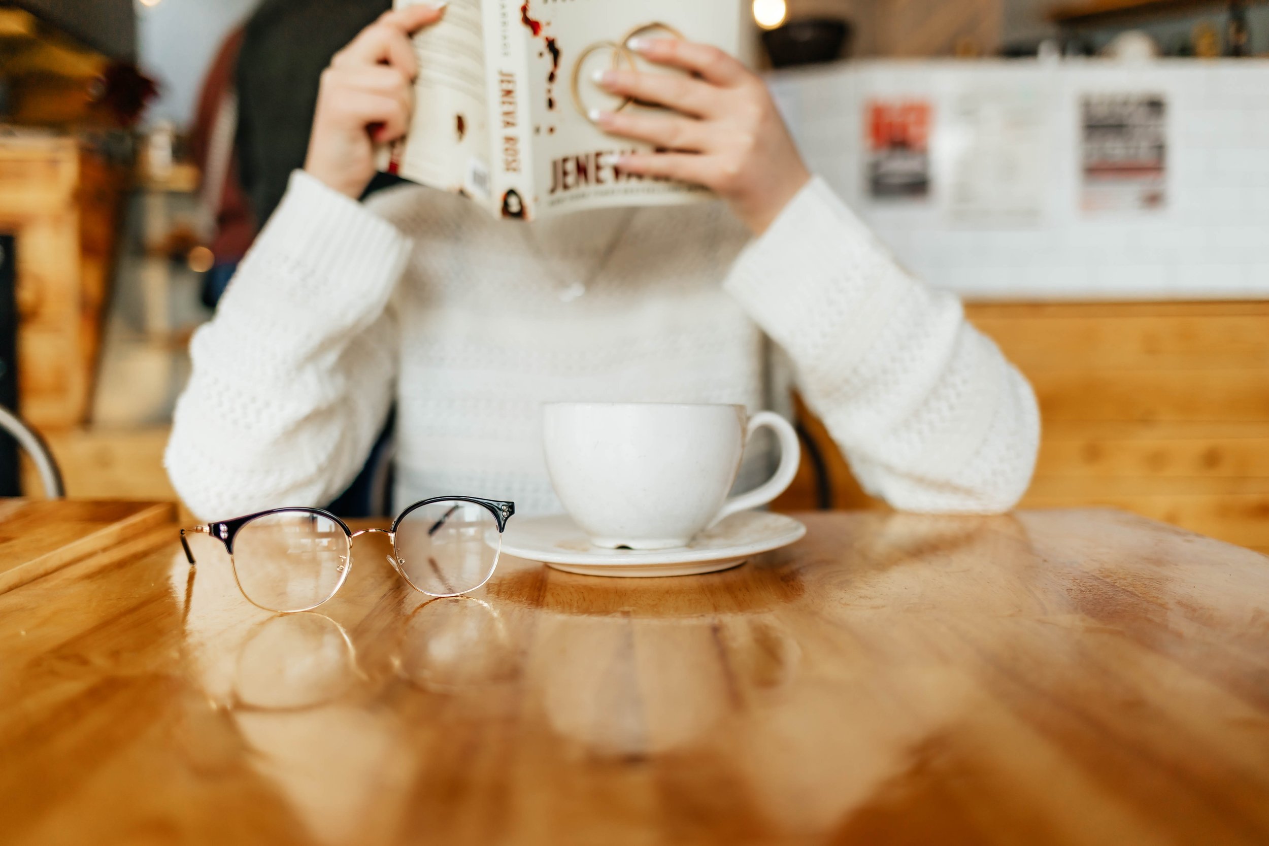 Three women sitting at a counter in a restaurant or cafe, with eyes closed, seemingly in a meditative or contemplative state, in a black and white photo.