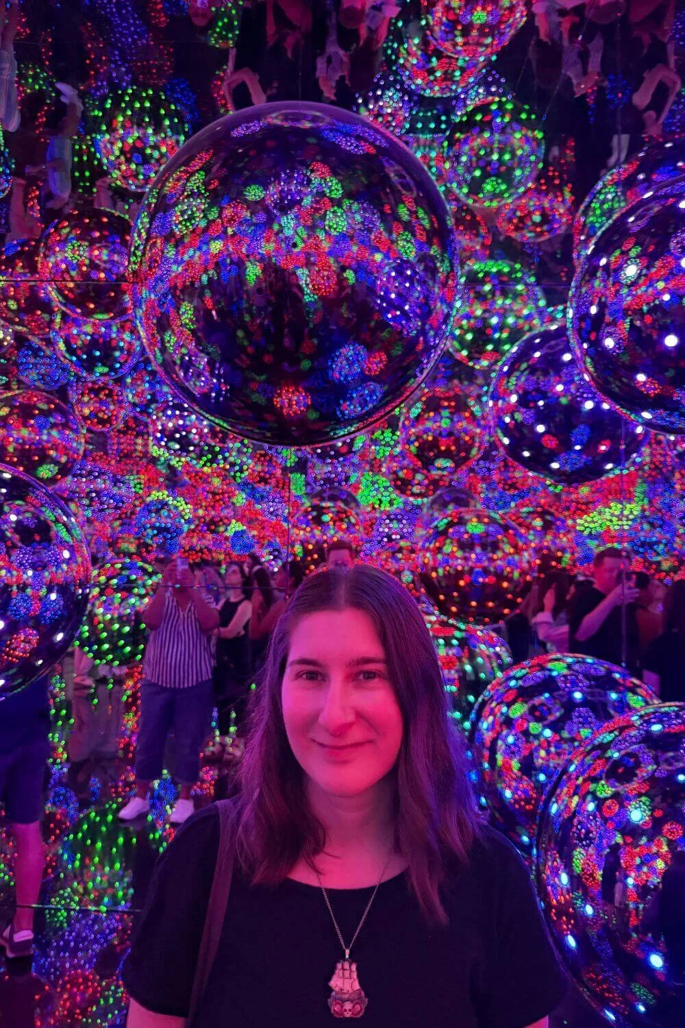 Sarah at an art gallery surrounded by mirror balls and flashing lights