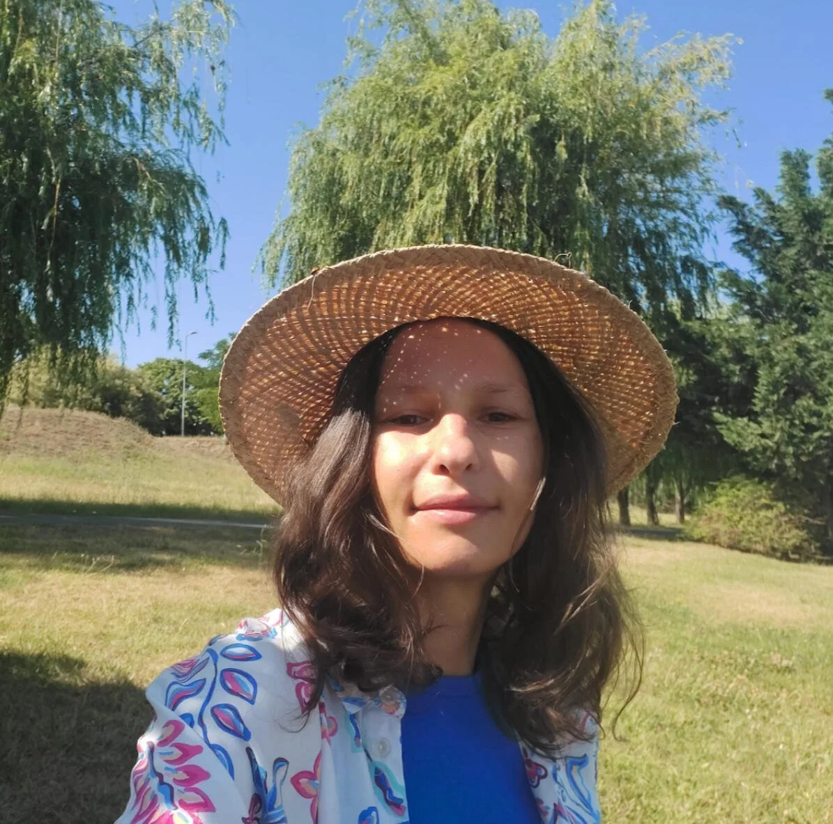 Copywriting services client feedback from Ioana, wellness guide, in a sun hat in a green field