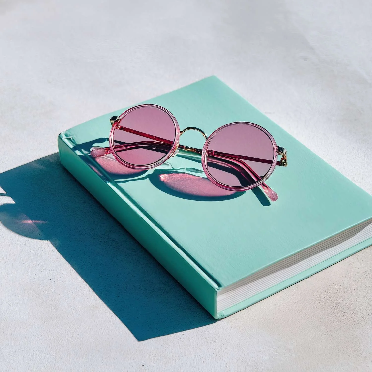 Blue hardcover notebook with purple-shade sunglasses resting on top