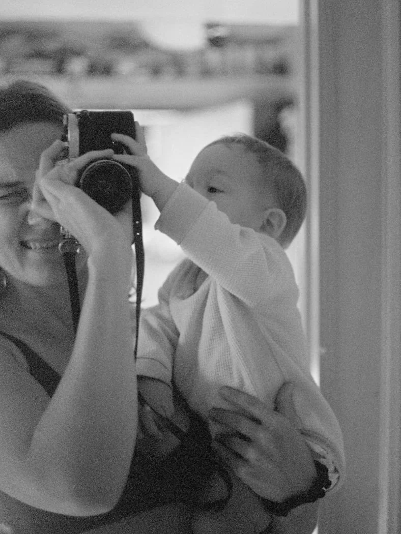 Moa Raud in black and white holding her camera and her baby