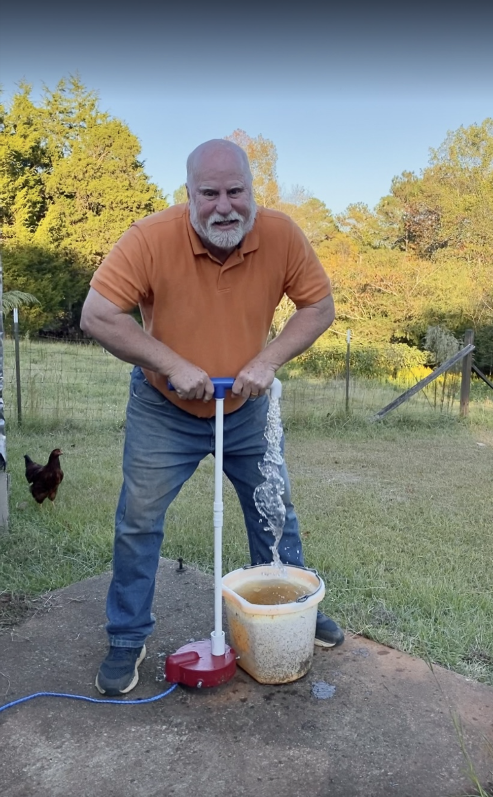 Keith operating his installed hand pump with water flowing into a bucket