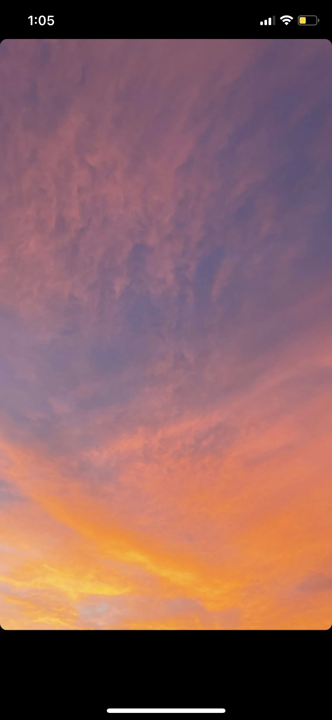 Colorful sky at sunset or sunrise with hues of purple, pink, orange, and yellow, and scattered clouds.